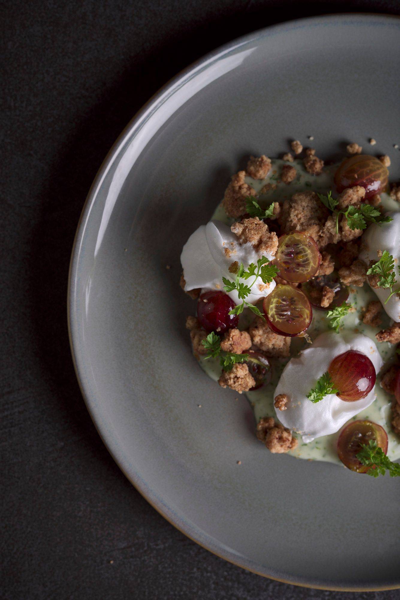 gooseberry and spelt crumble with chervil custard on a gray plate with gray sapienstone top