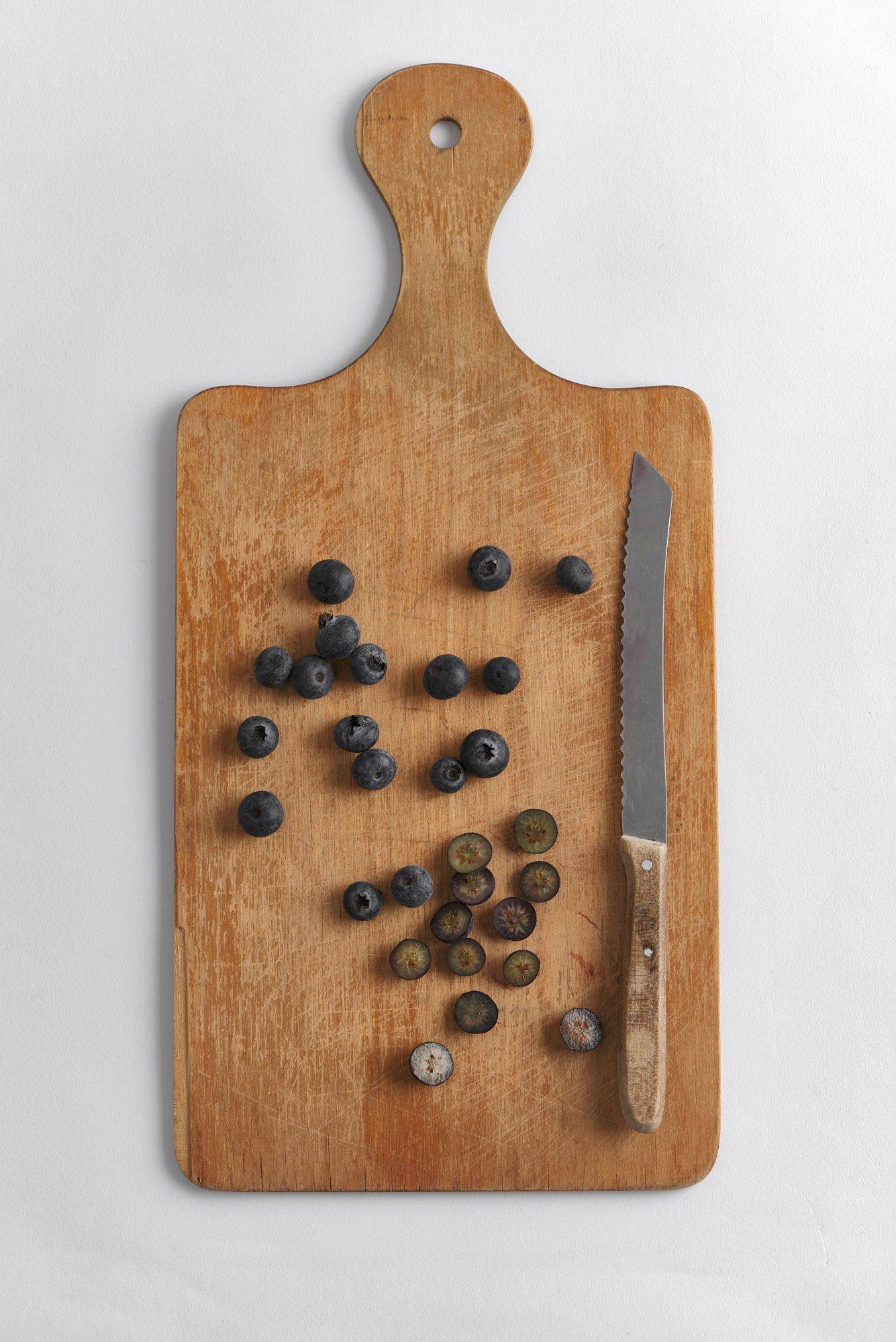 blueberries on a wooden board on a gray plate with white background