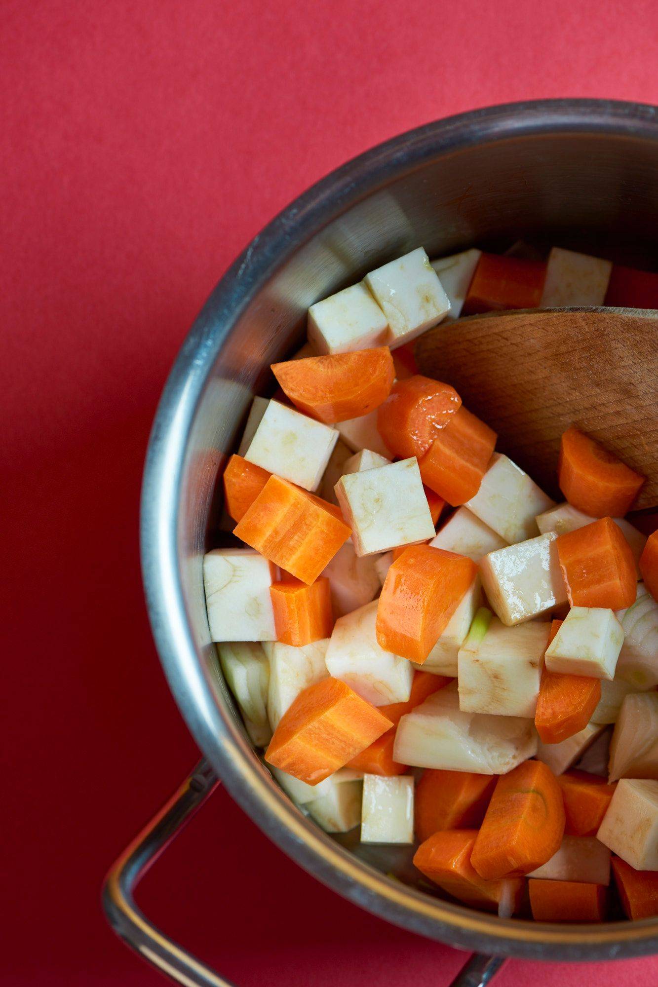 carrots and celeriac in a pot with red background