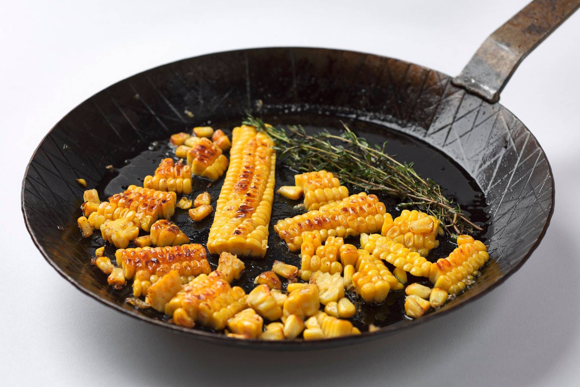 roasted corn in a cast iron pan with white background