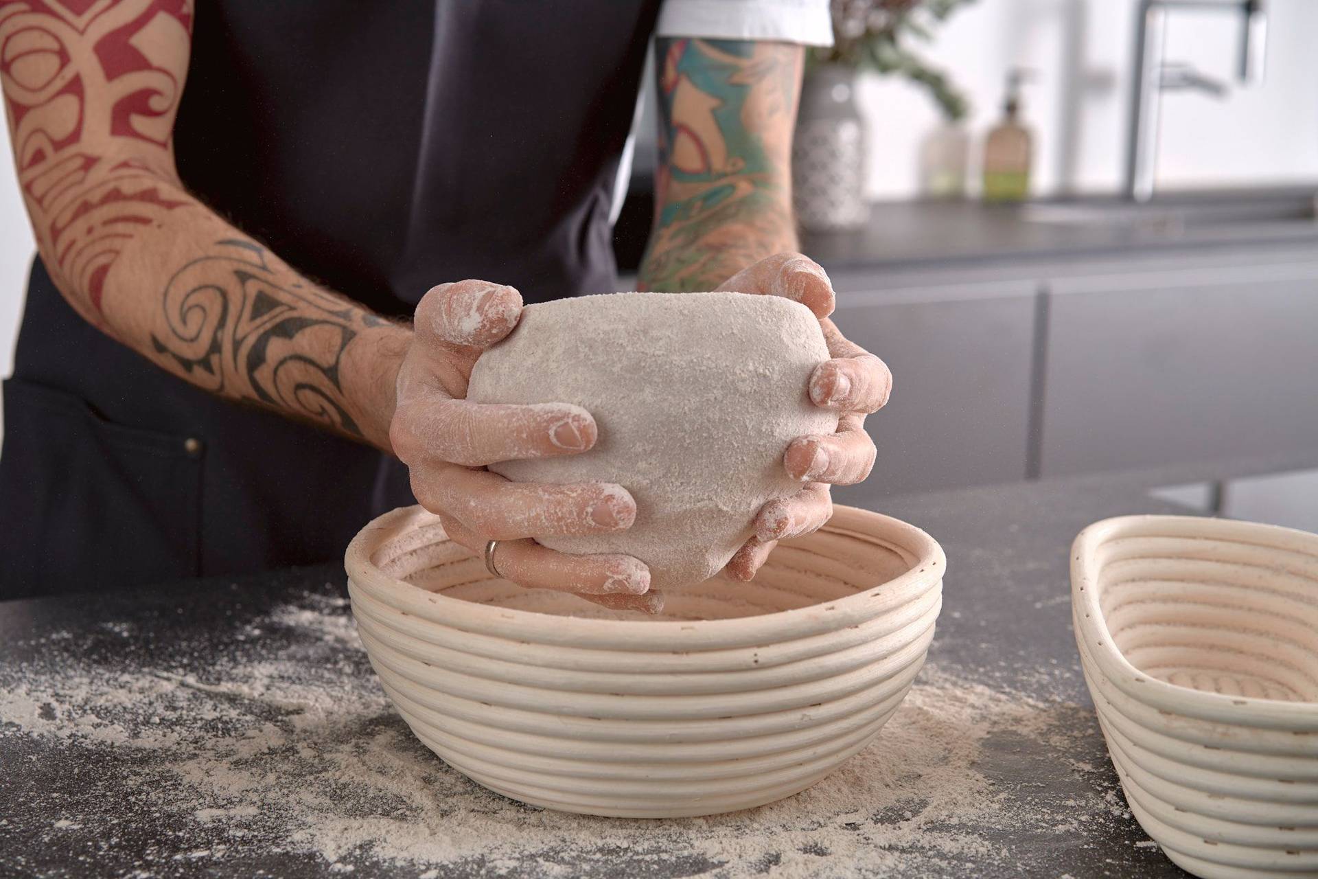 man is putting rye sourdough bread into proofing basket in home kitchen