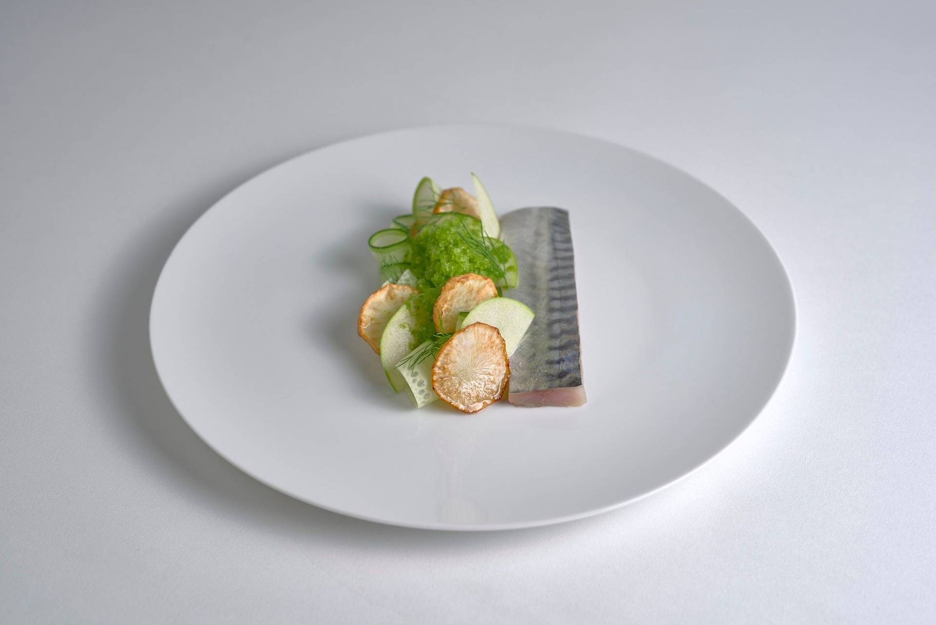 cured mackerel with jerusalem artichokes and dill granita on a white plate with white background