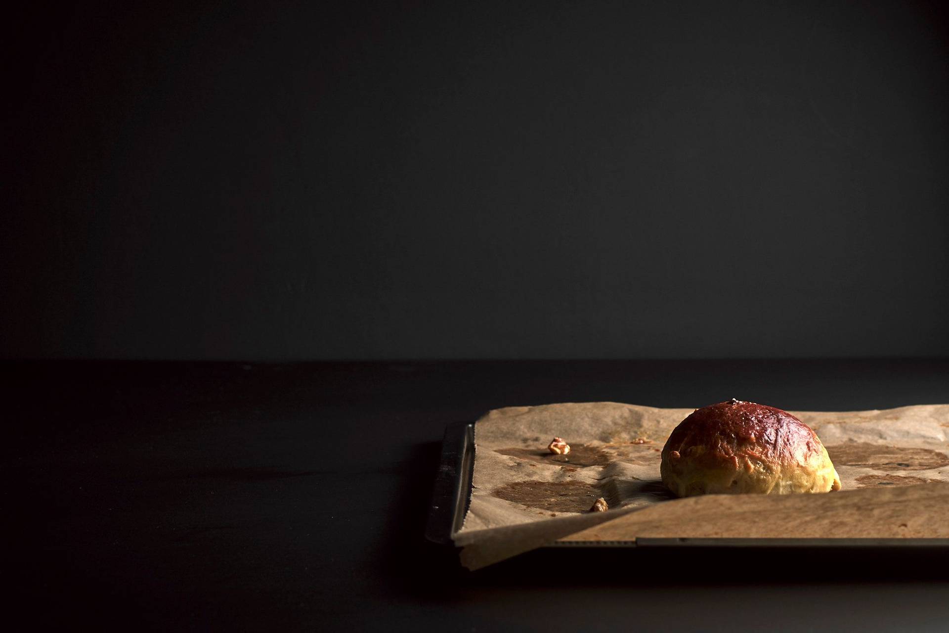 ein brioche brötchen mit walnüssen auf einem backblech mit schwarzem hintergrund