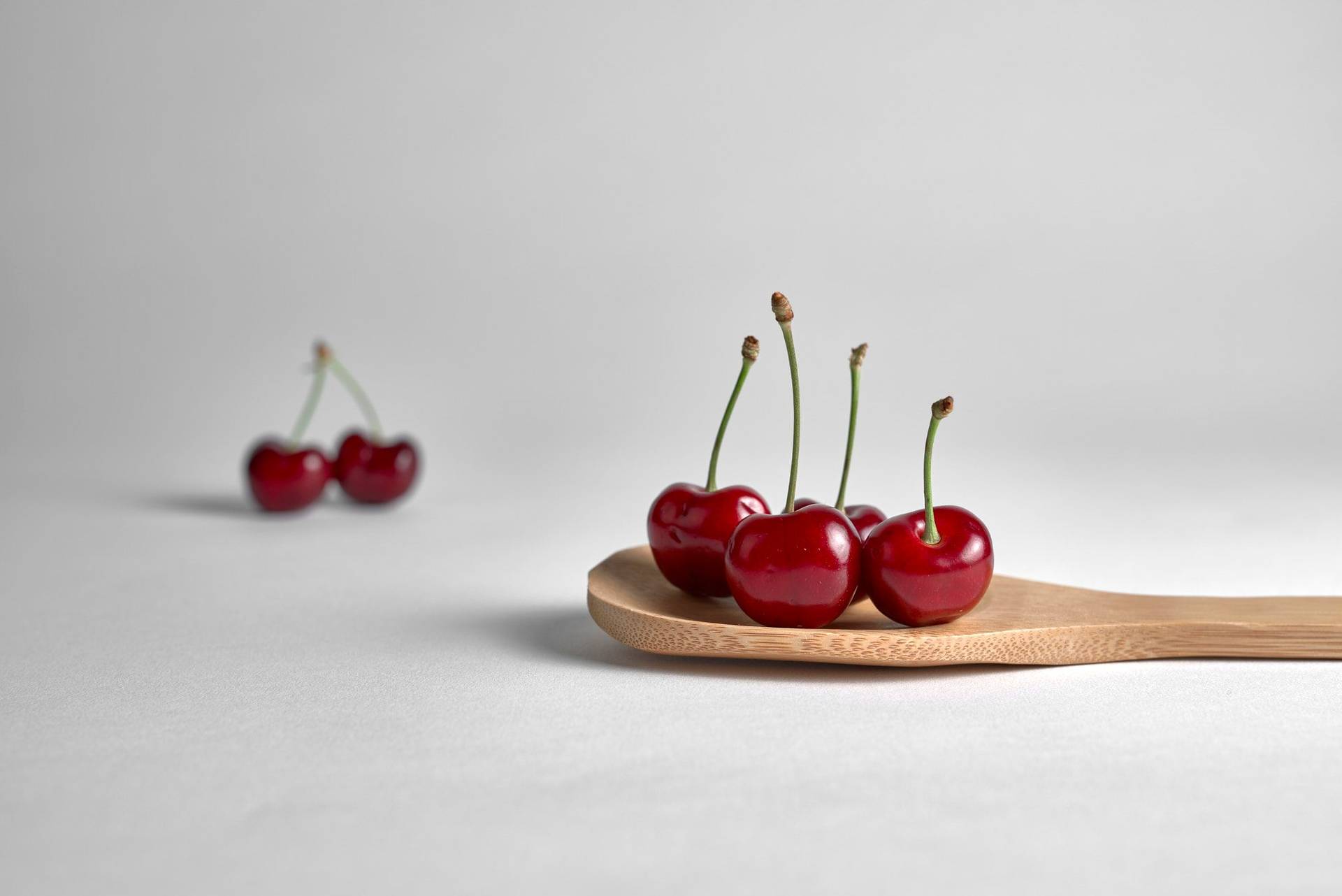 fresh cherries on a wooden spoon with white background