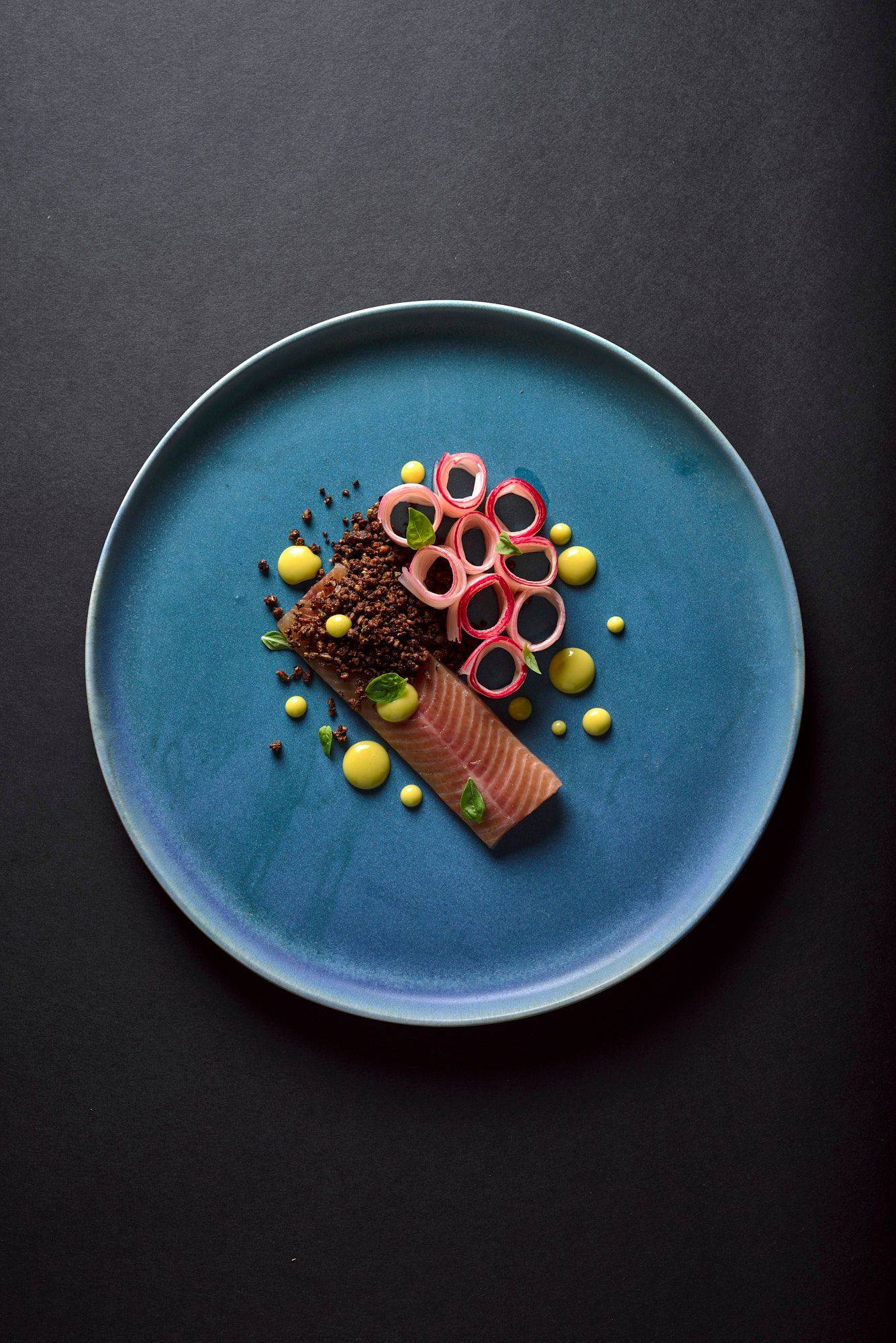 basil and orange cured char with rhubarb and tea mayonnaise on a blue plate with black background