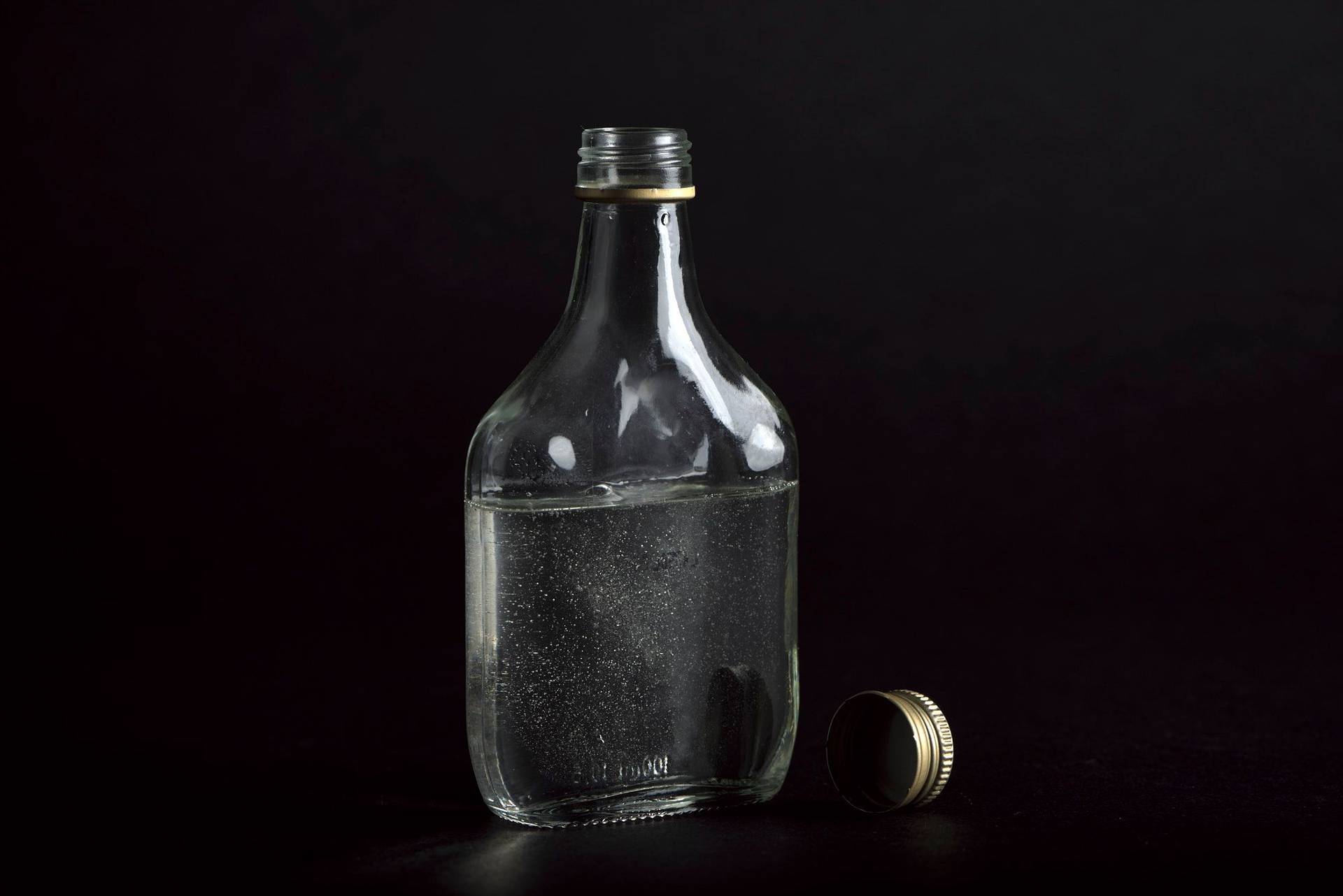 a glass bottle of sugar syrup on black background