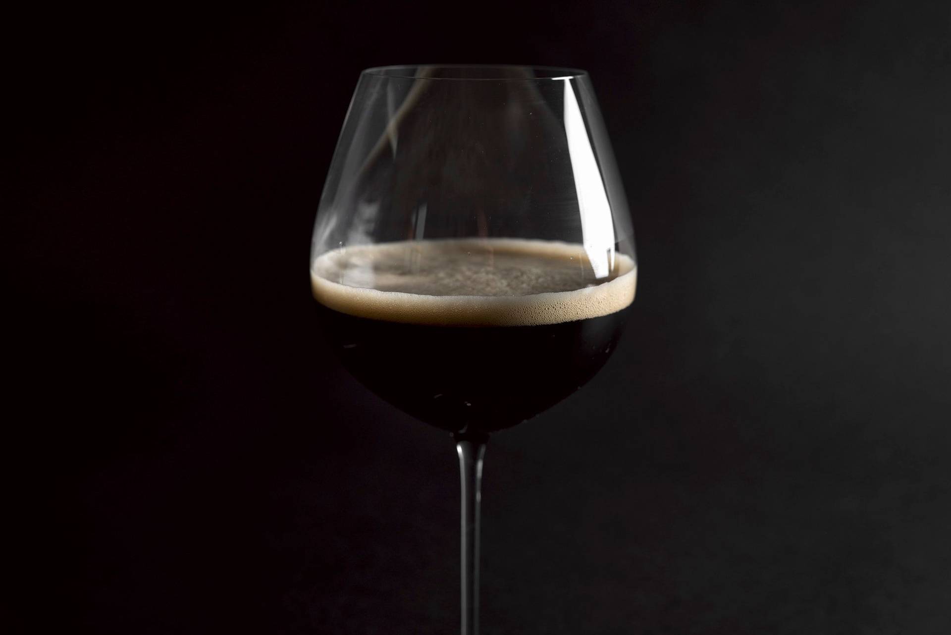 a glass of dark beer with black background
