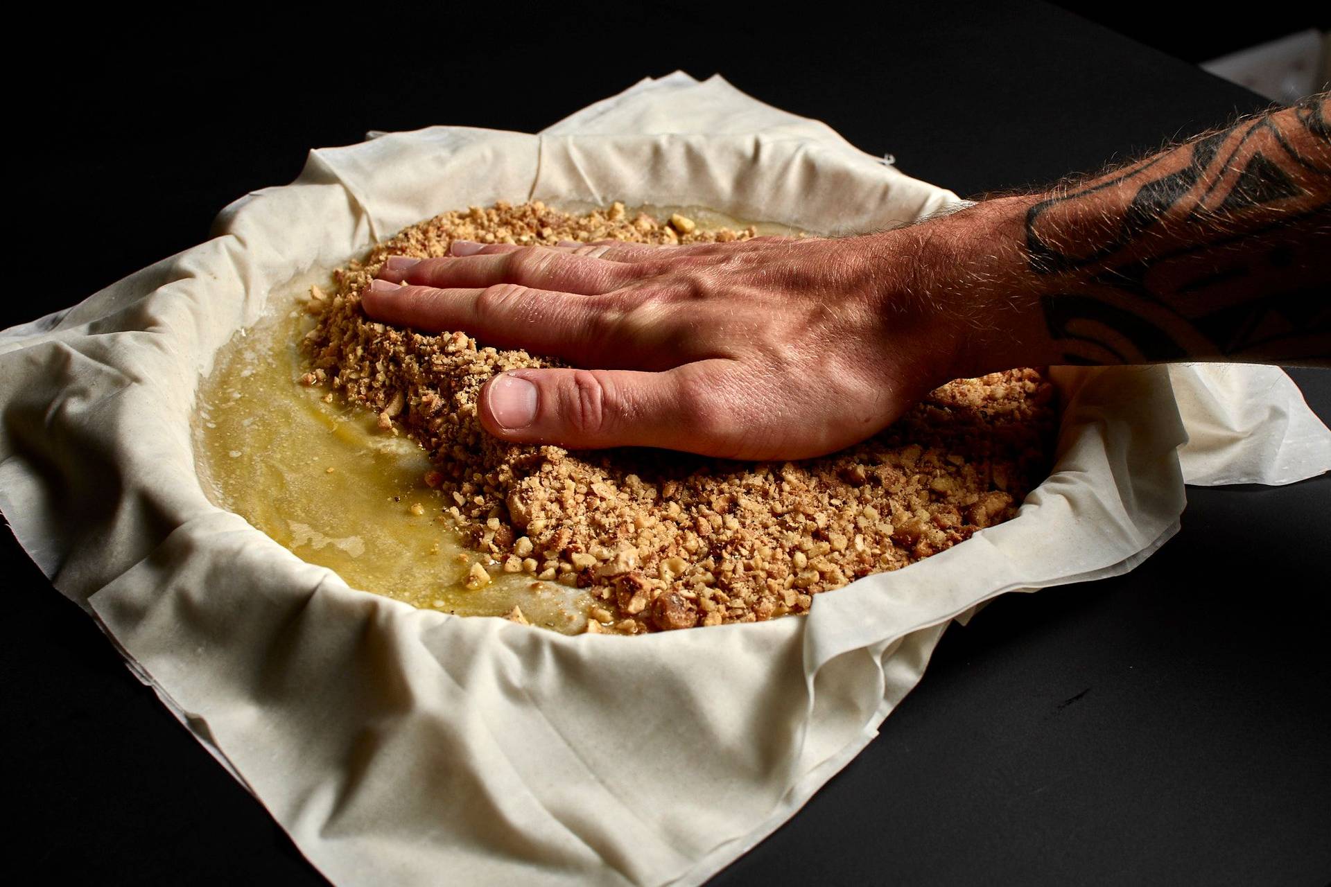 herstellung von baklava mit haselnüssen und walnüssen in einer backform auf schwarzem hintergrund