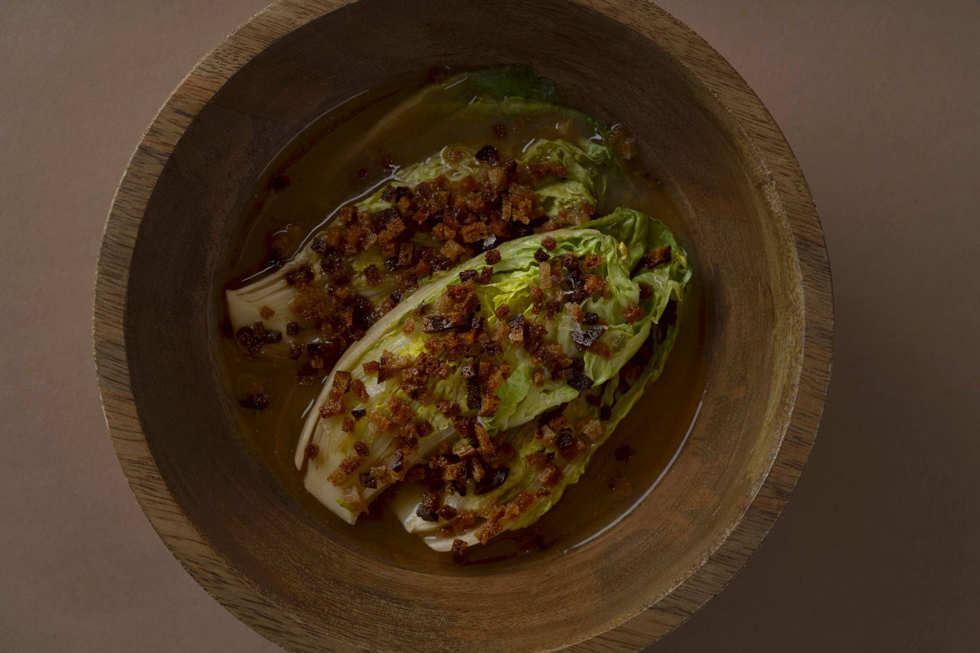 romaine lettuce with miso broth and sourdough in a wooden bowl with brown background