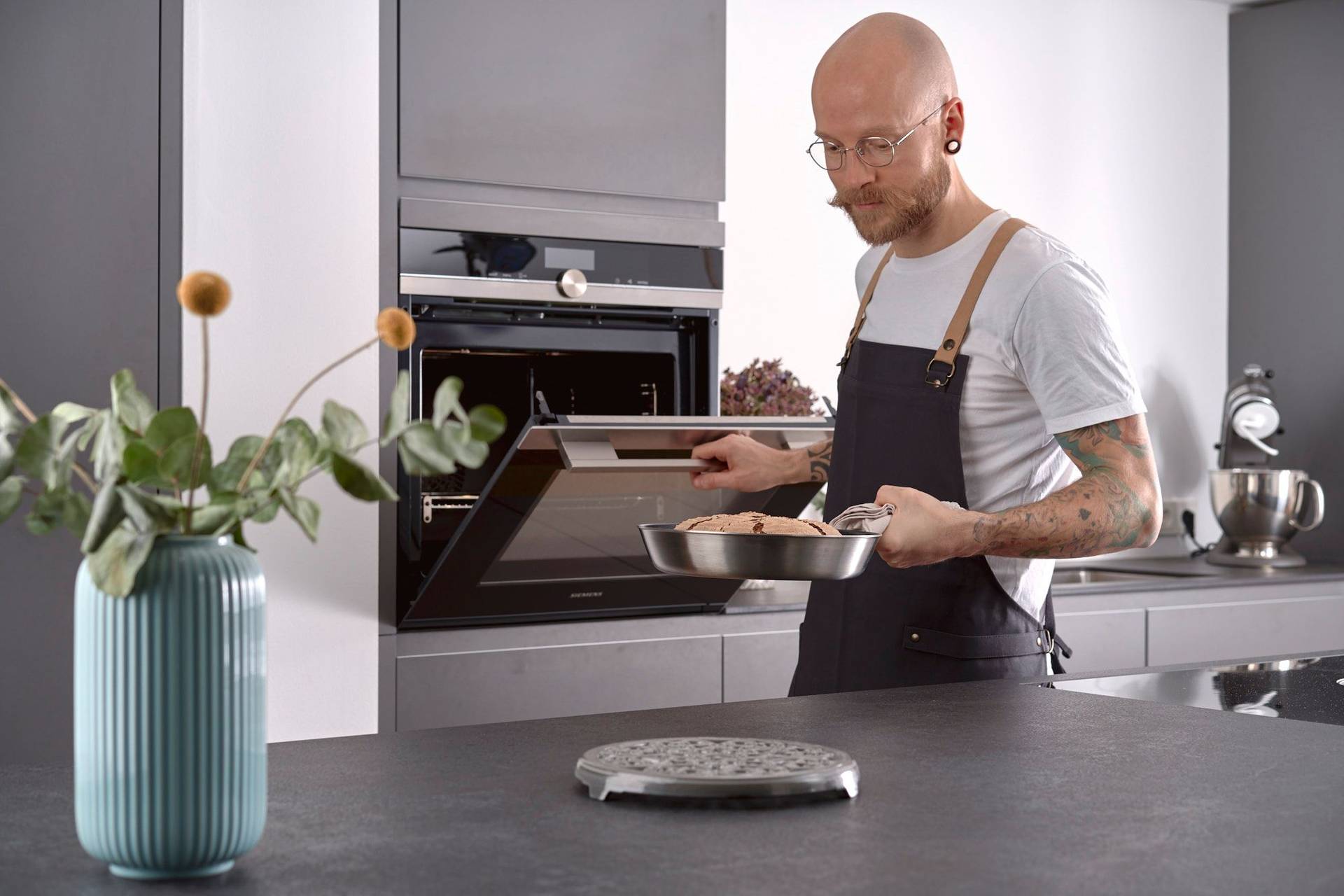 man holds a pan baked rye sourdough bread in home kitchen