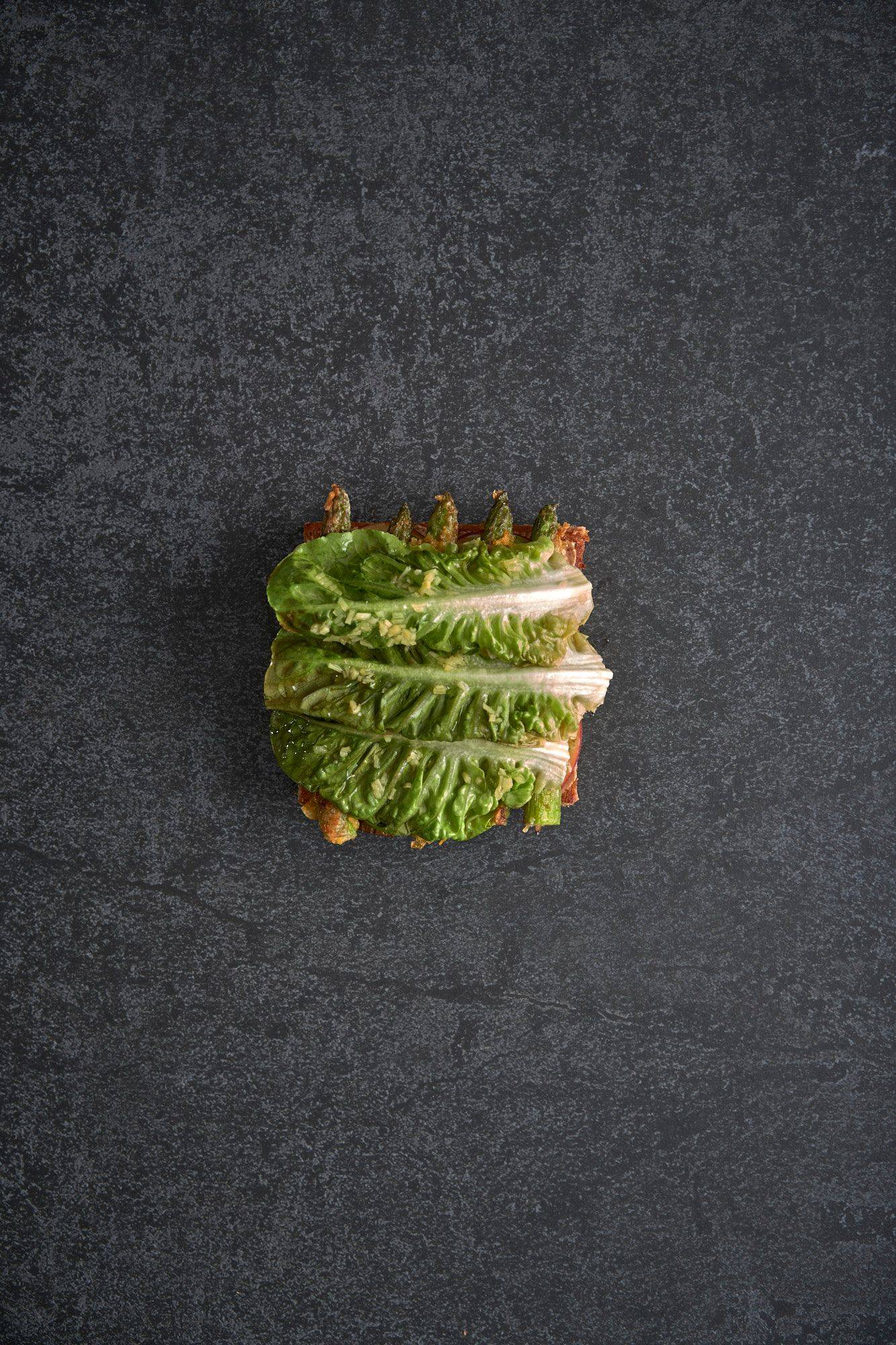 assembling a vegetarian asparagus katsu sando with nectarine and mint mayonnaise on a gray sapienstone top