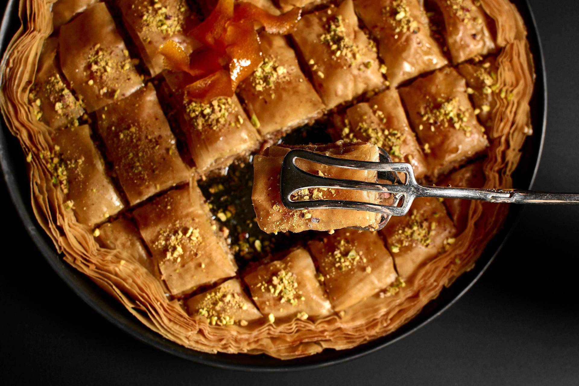 baklava mit haselnüssen und walnüssen in einer backform auf schwarzem hintergrund