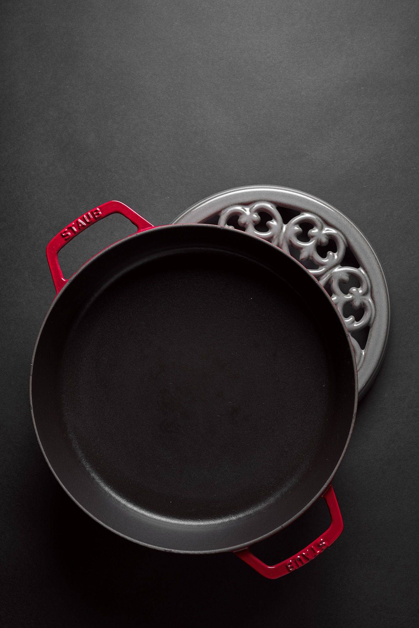 red staub la cocotte cast iron pot and coaster on black background