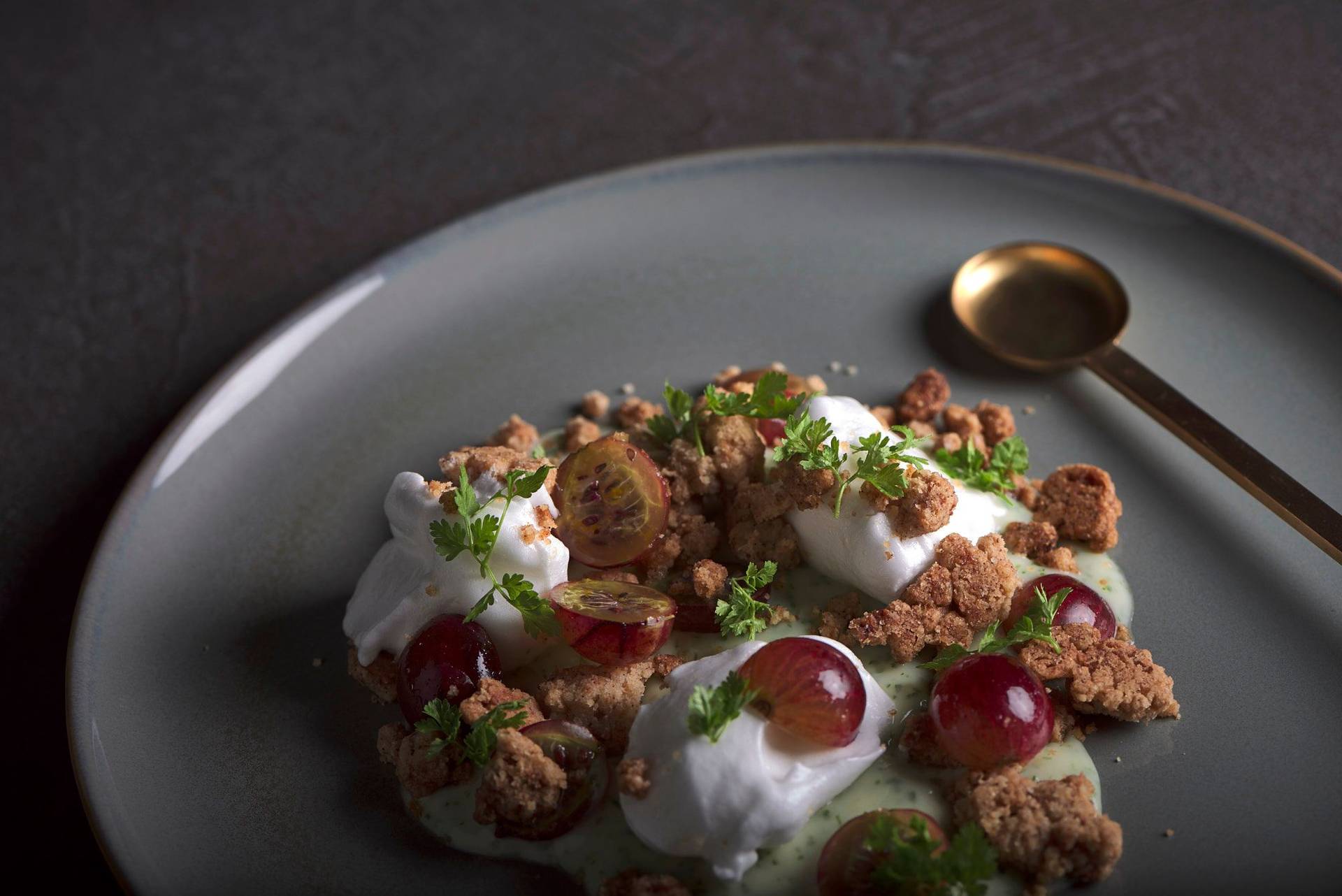 gooseberry and spelt crumble with chervil custard on a gray plate with gray sapienstone top