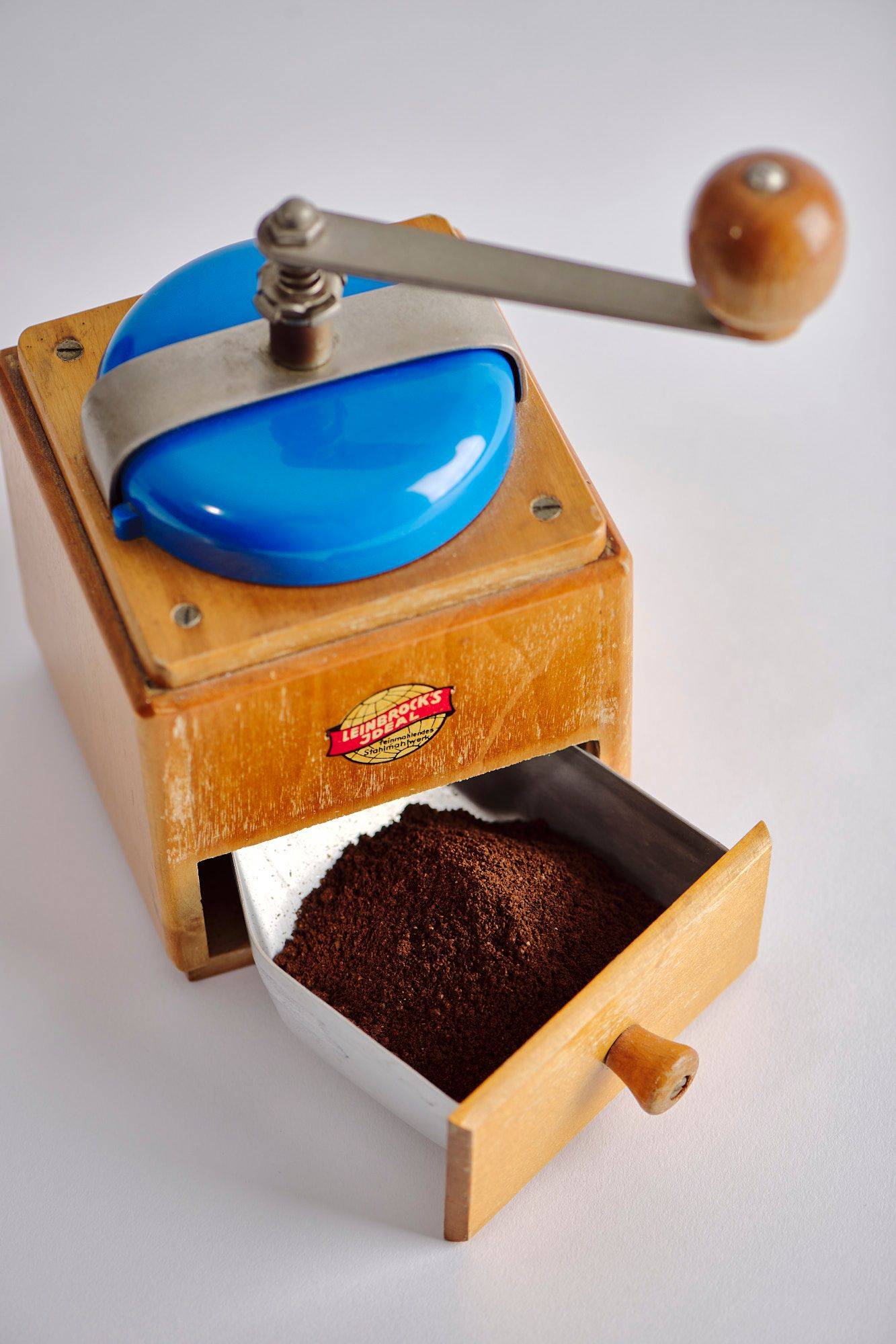 ground coffee in a vintage hand mill with white background