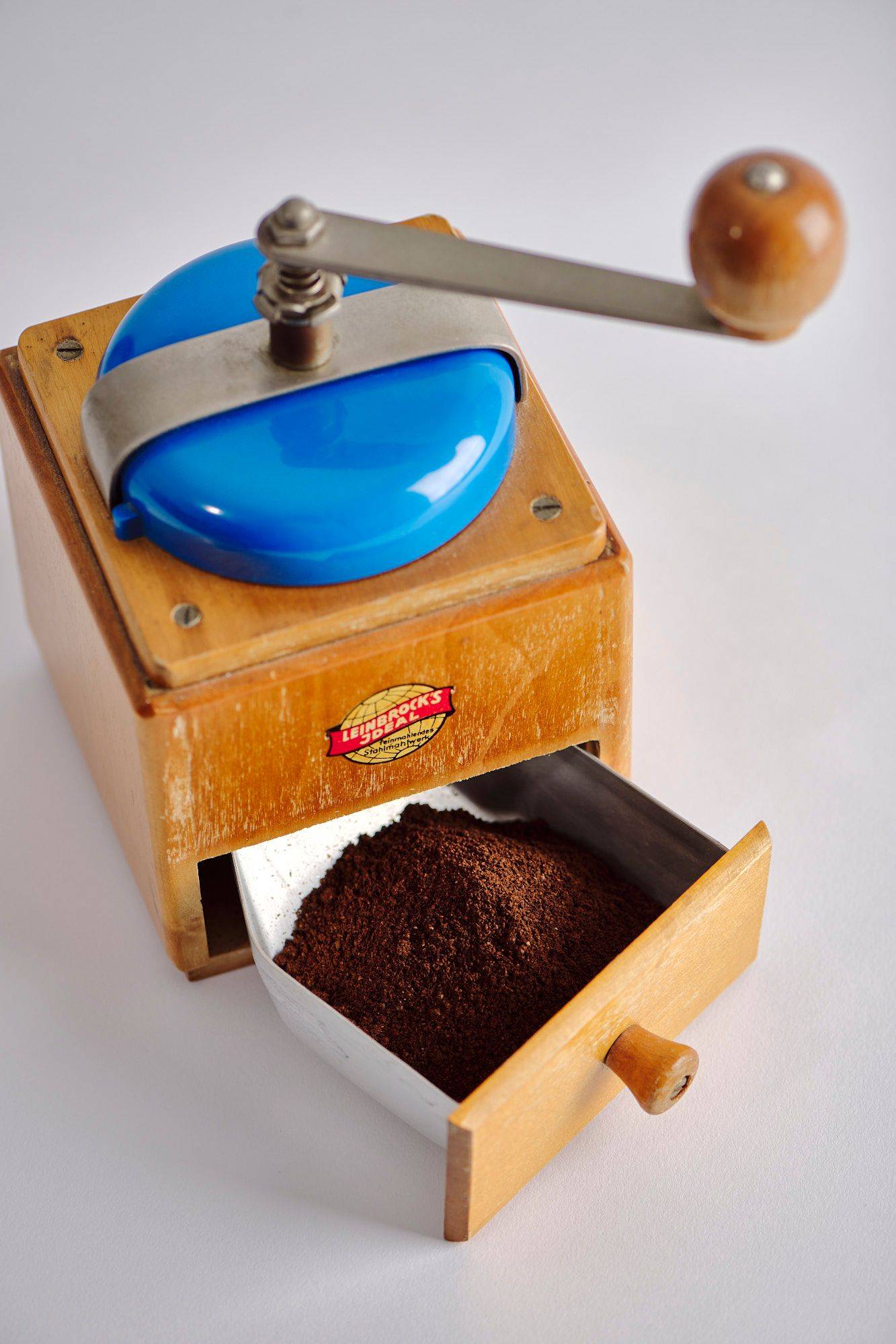ground-coffee ground coffee in a vintage hand mill with white background