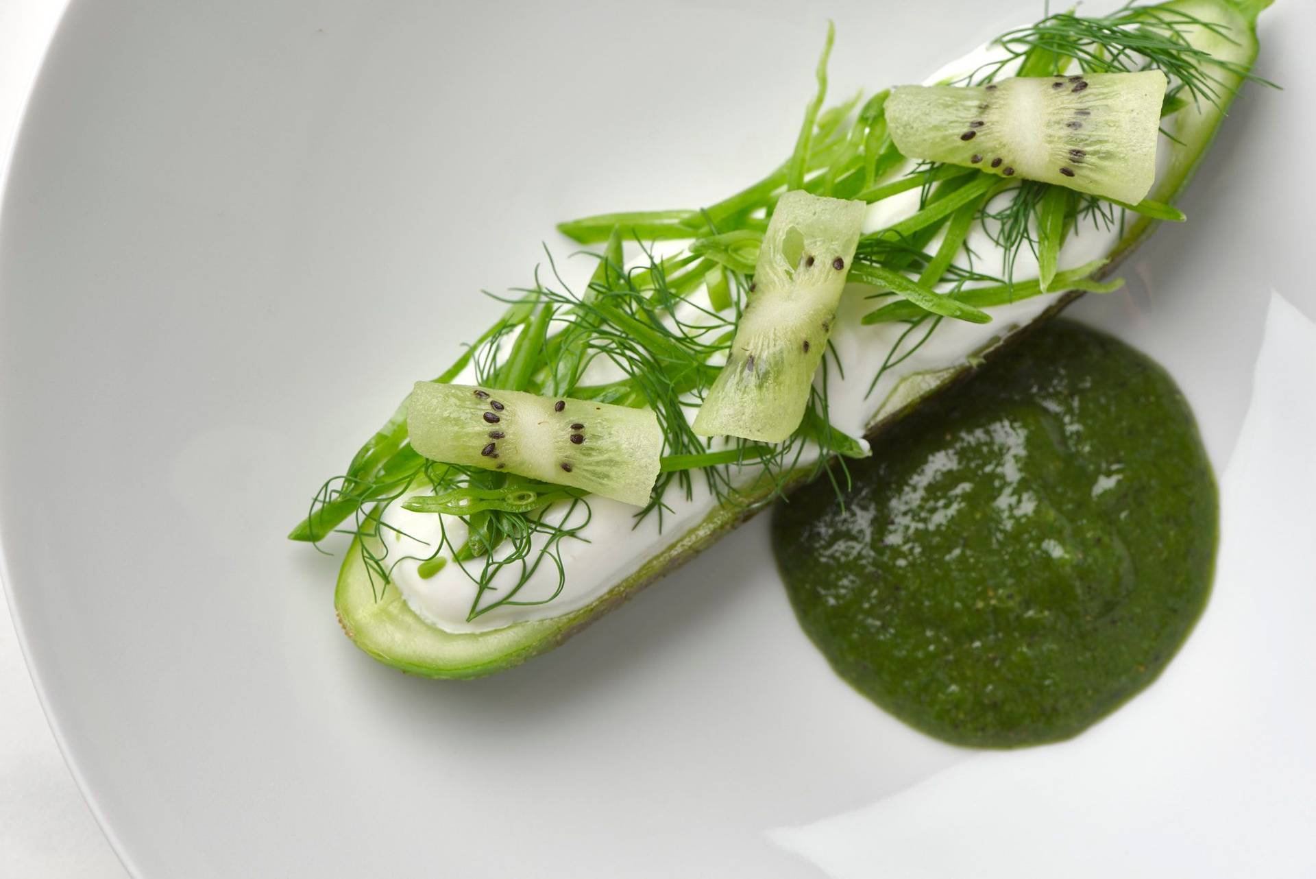 charred cucumber with kiwi salsa skyr and dill on a white plate with a marbled sapienstone top