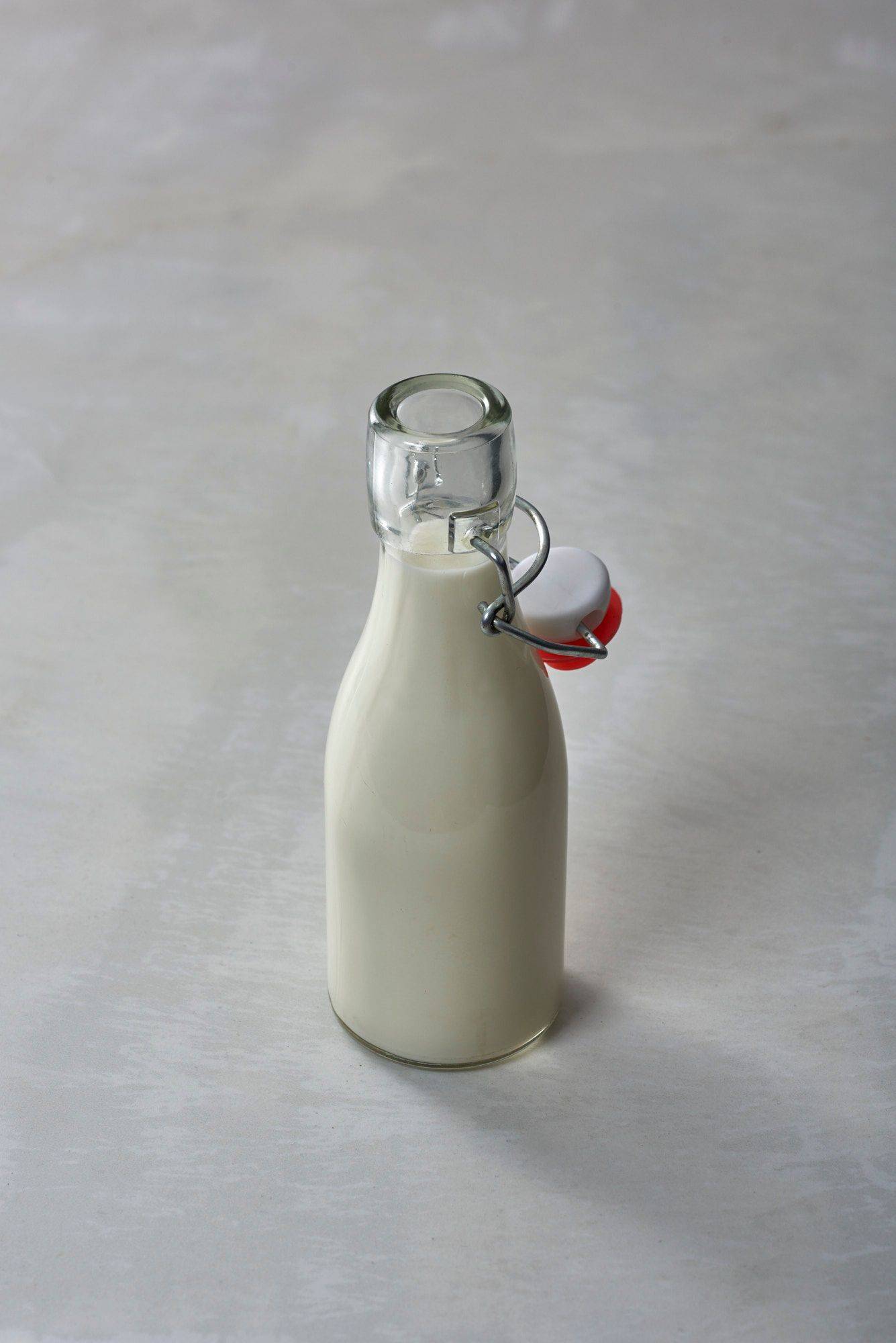 eine kleine glasflasche mit milch mit weißem sapienstone top