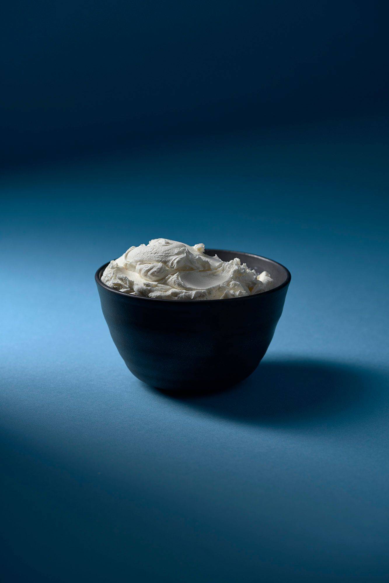 mascarpone käse in grauer keramik schale mit blauem hintergrund