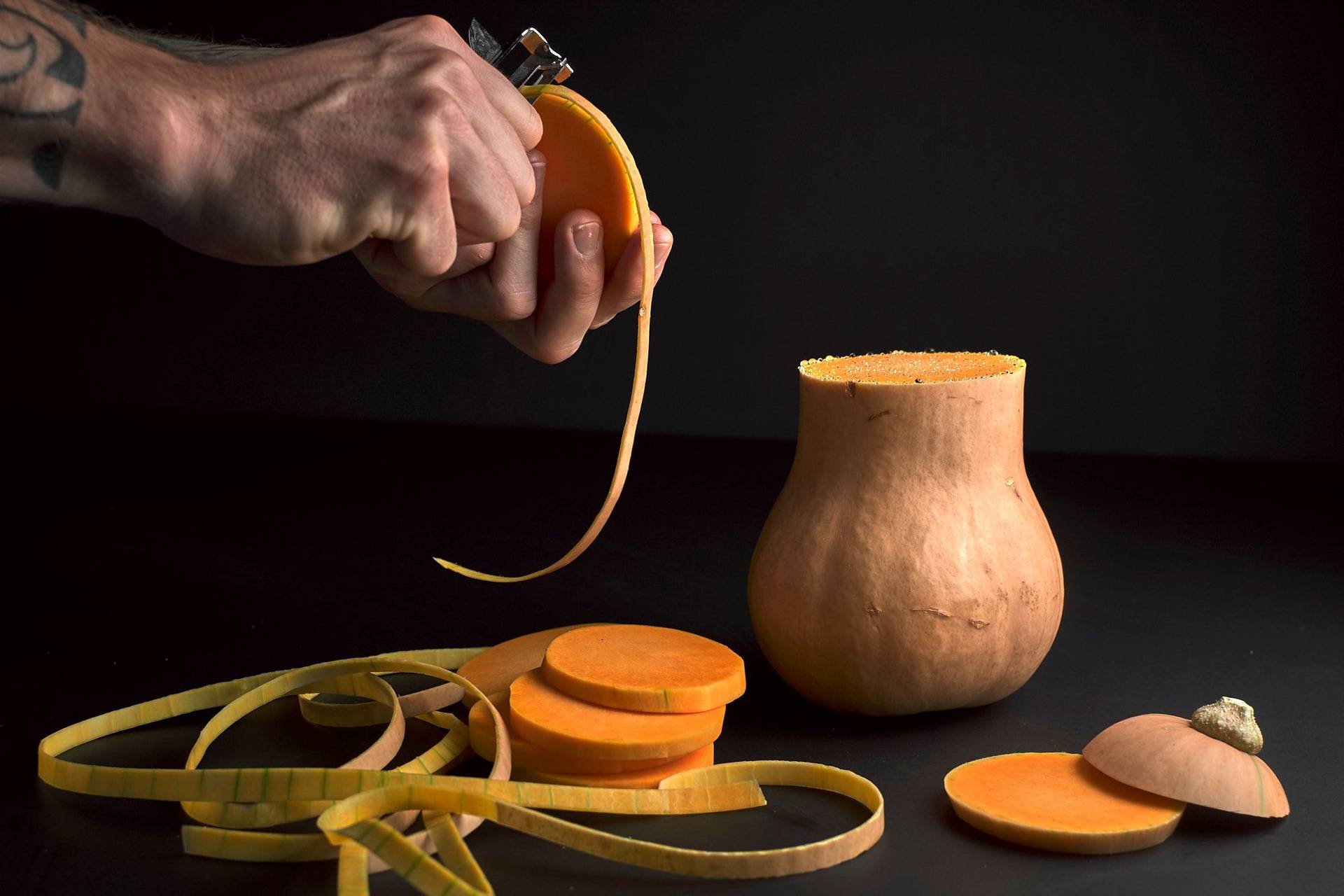  two hands peeling a pumpkin with black background