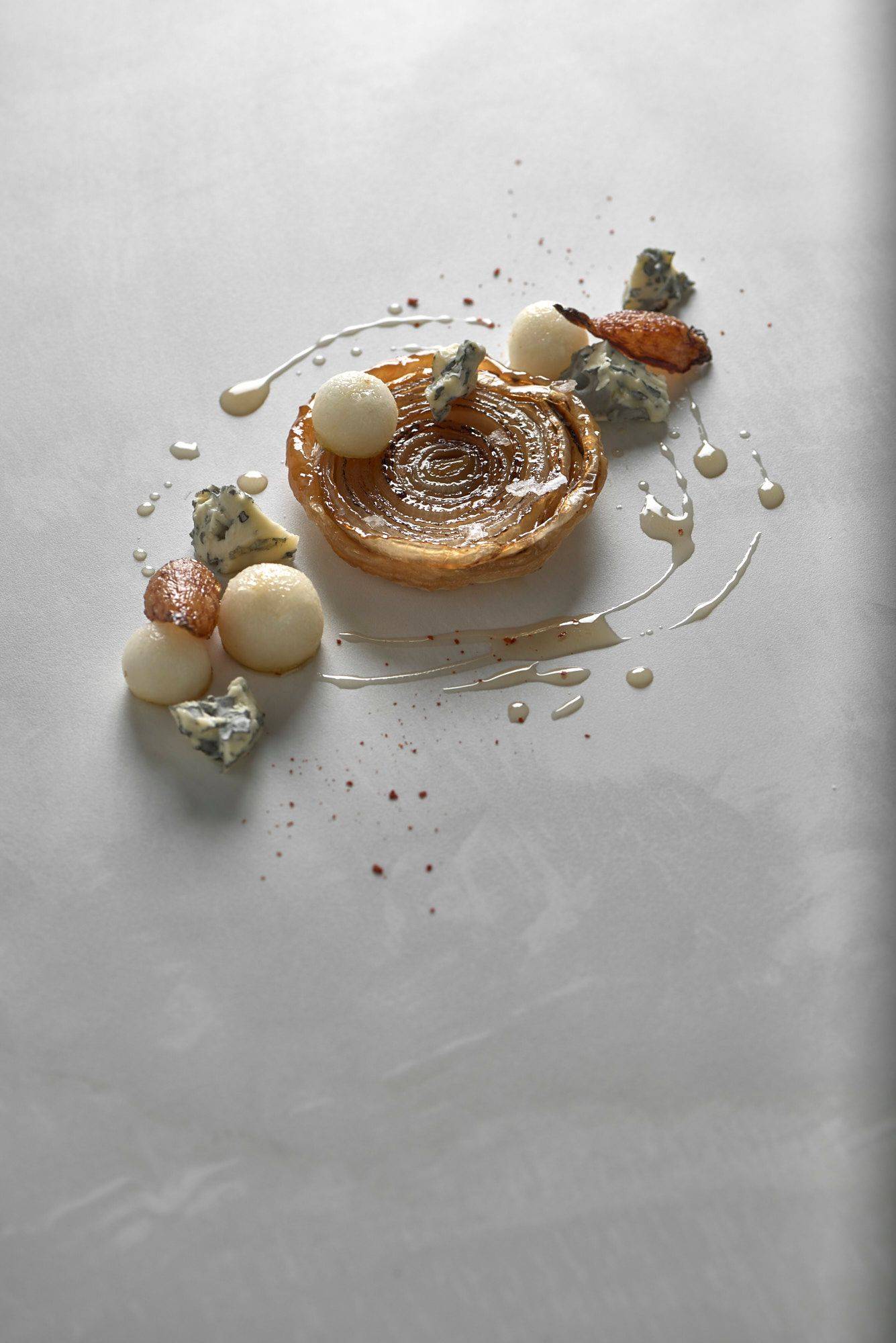 onion tarte tatin with blue cheese and pear on a white stone table