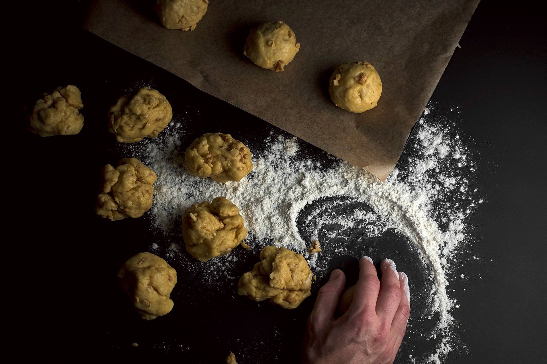 hand forming brioche buns with walnuts on a black table