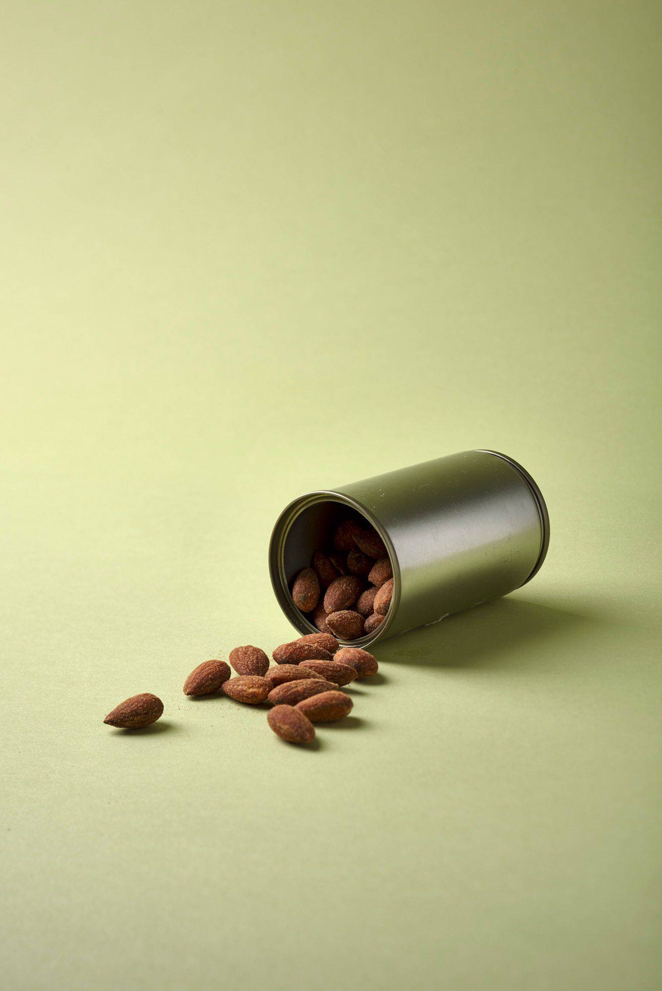 a can with smoked almonds with green background