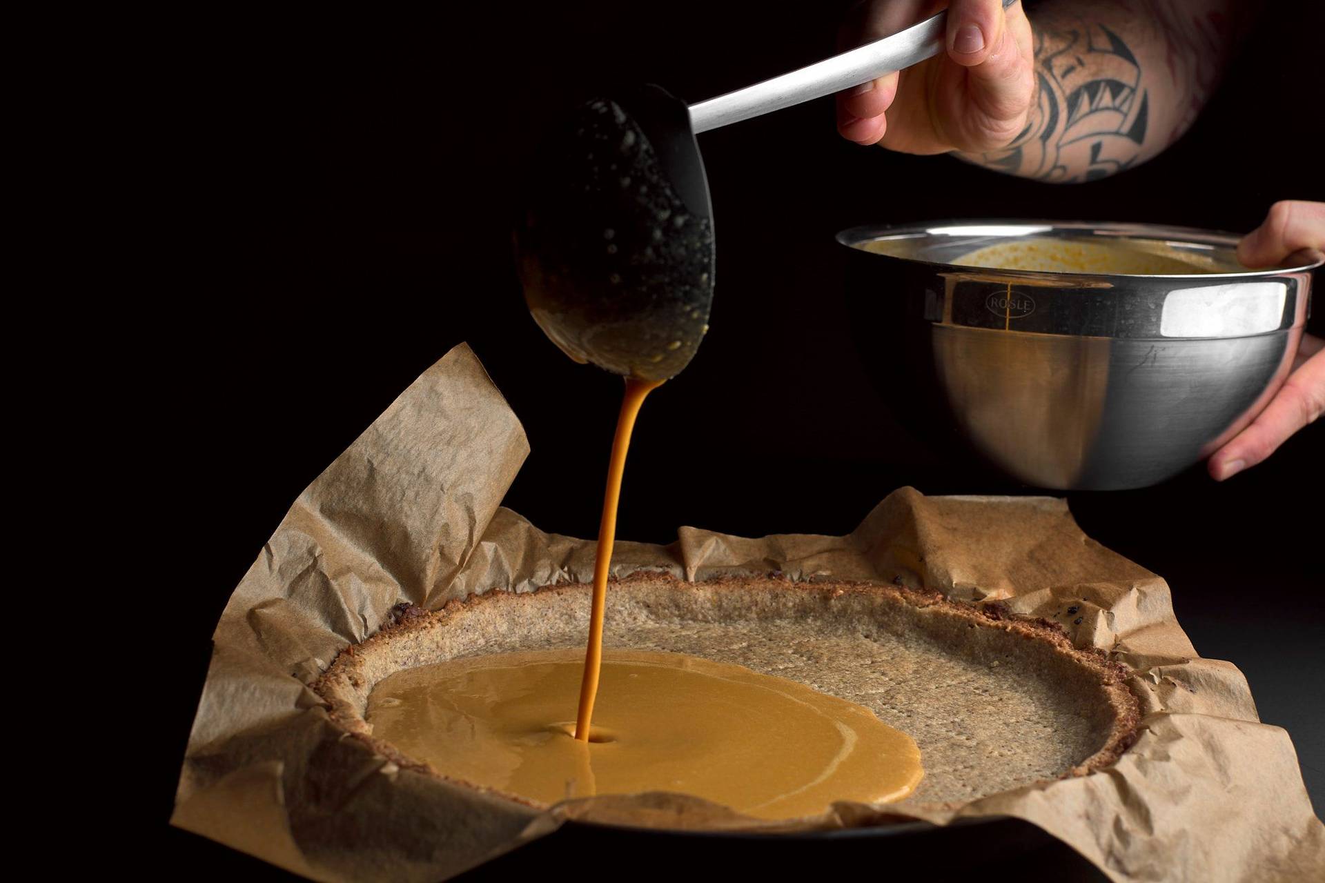 filling pumpkin pie on black background