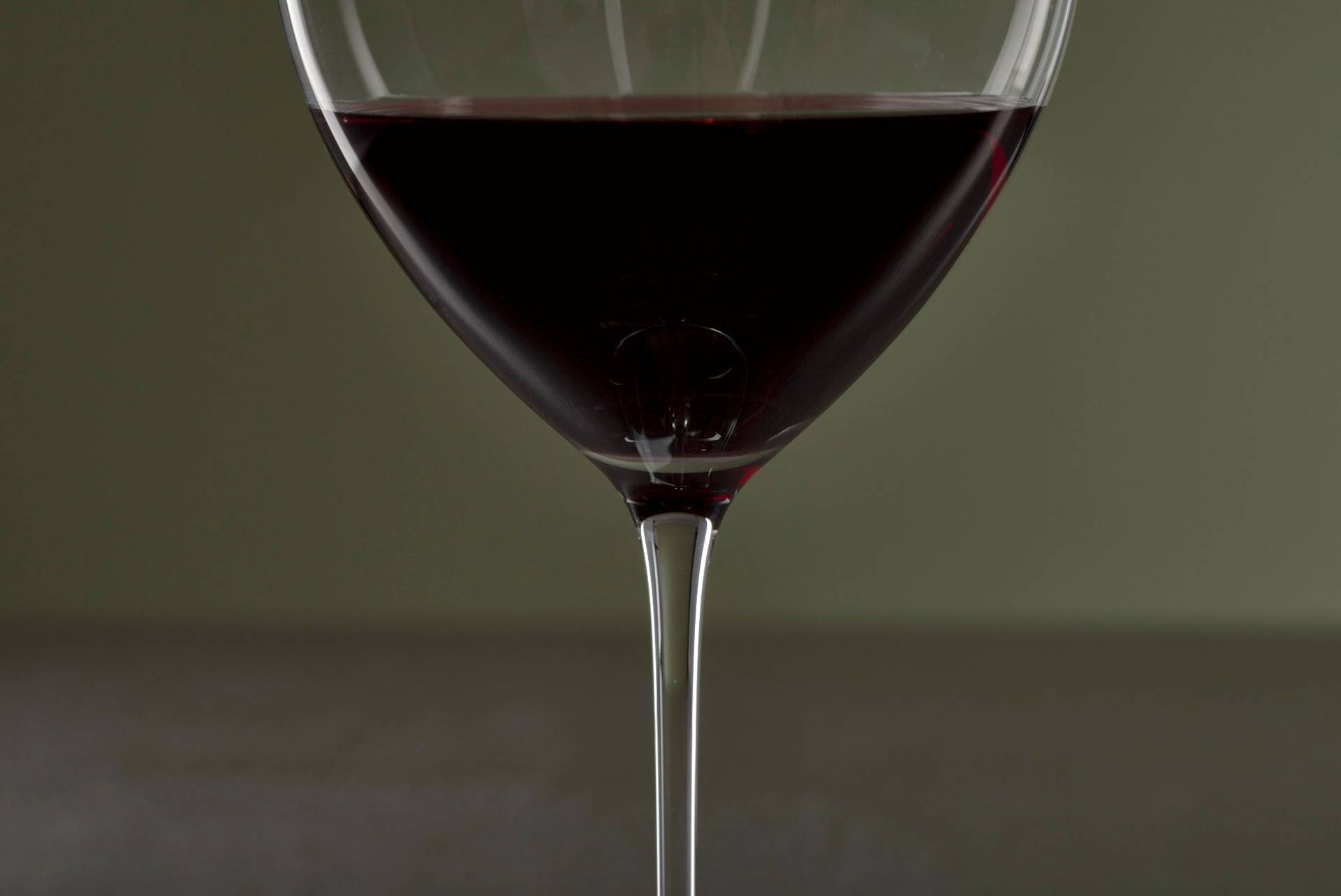 a glass of french red wine on a gray sapienstone top with green background