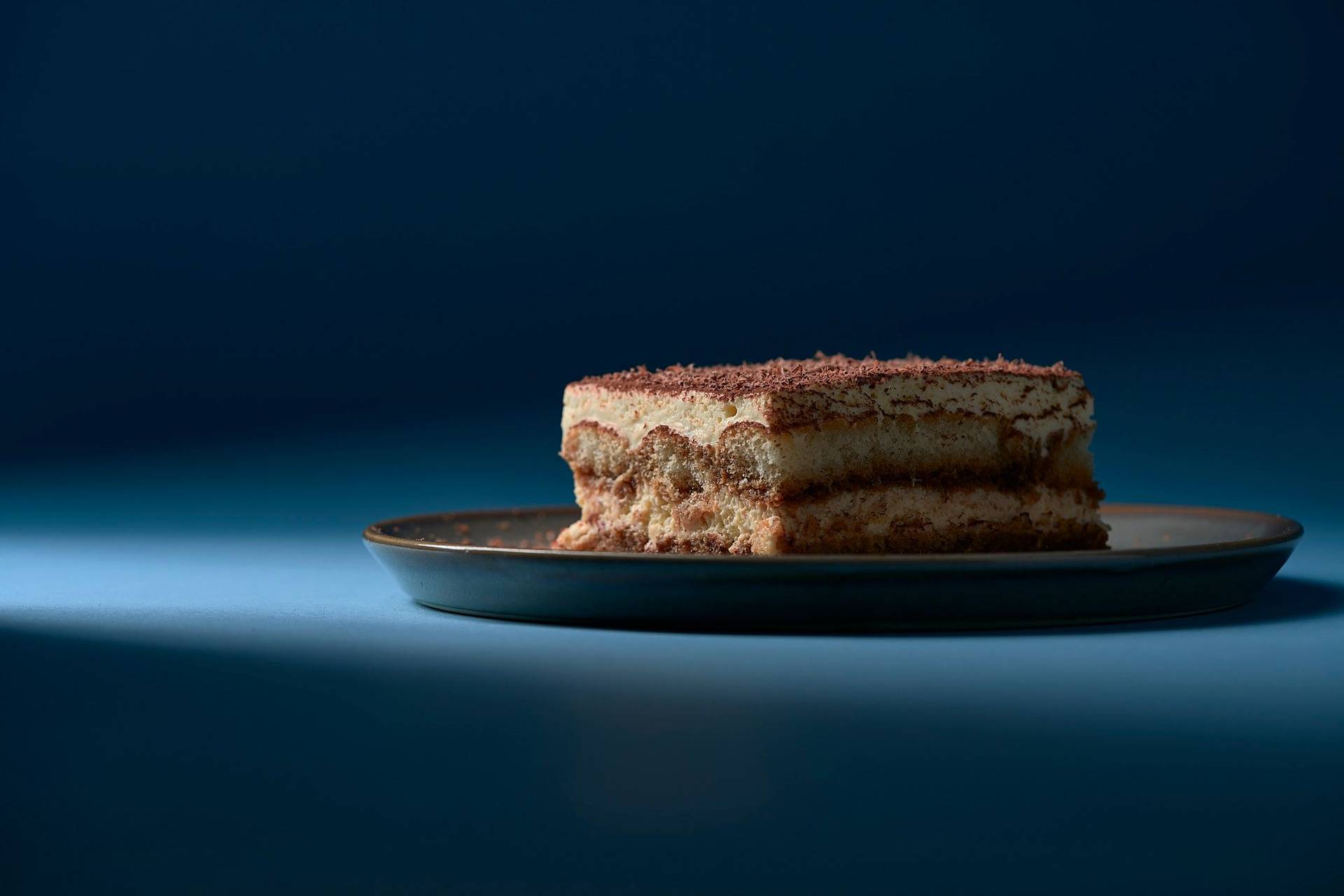 original italienisches tiramisu dessert auf grauem teller mit blauem hintergrund