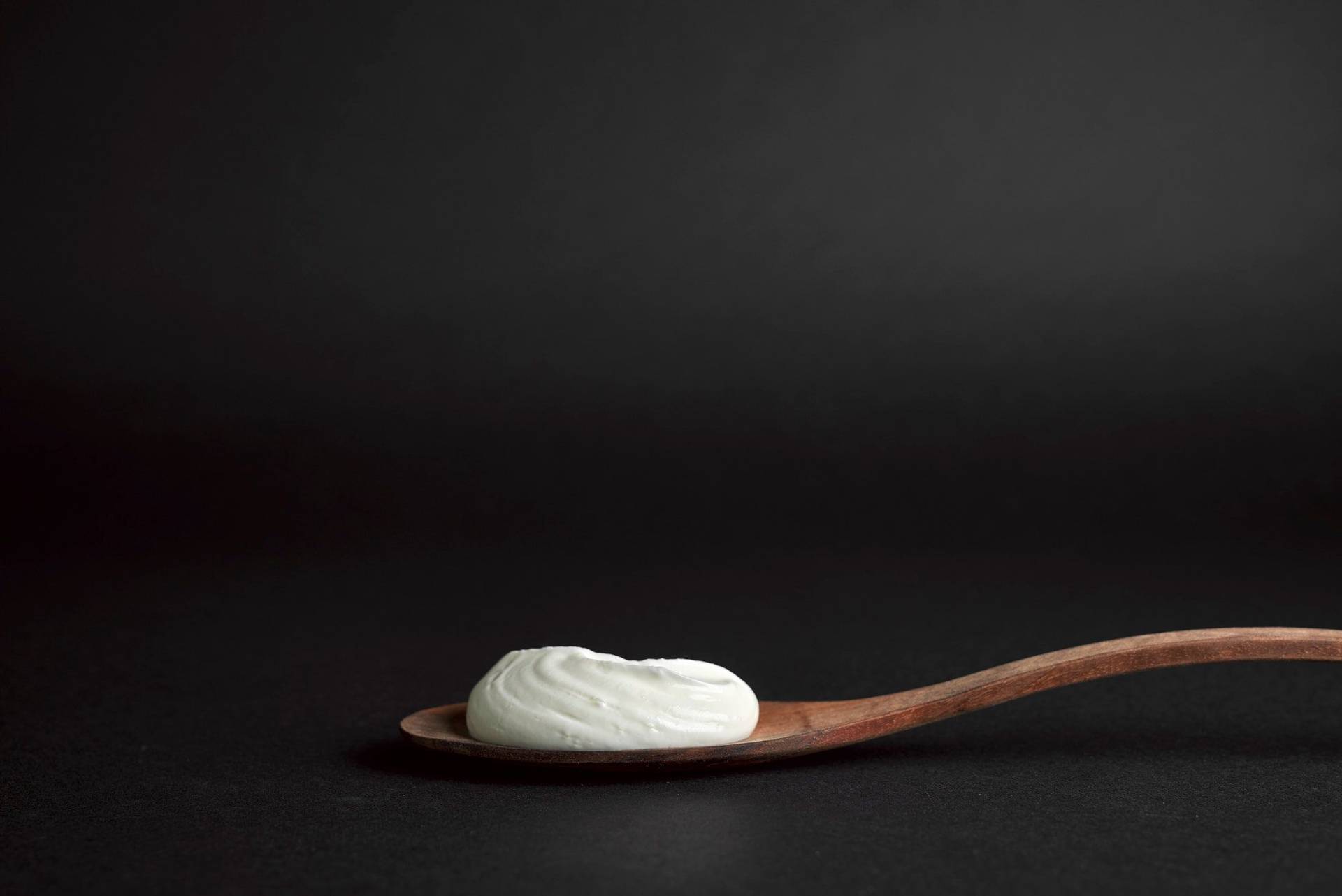 a wooden spoon with skyr with black background