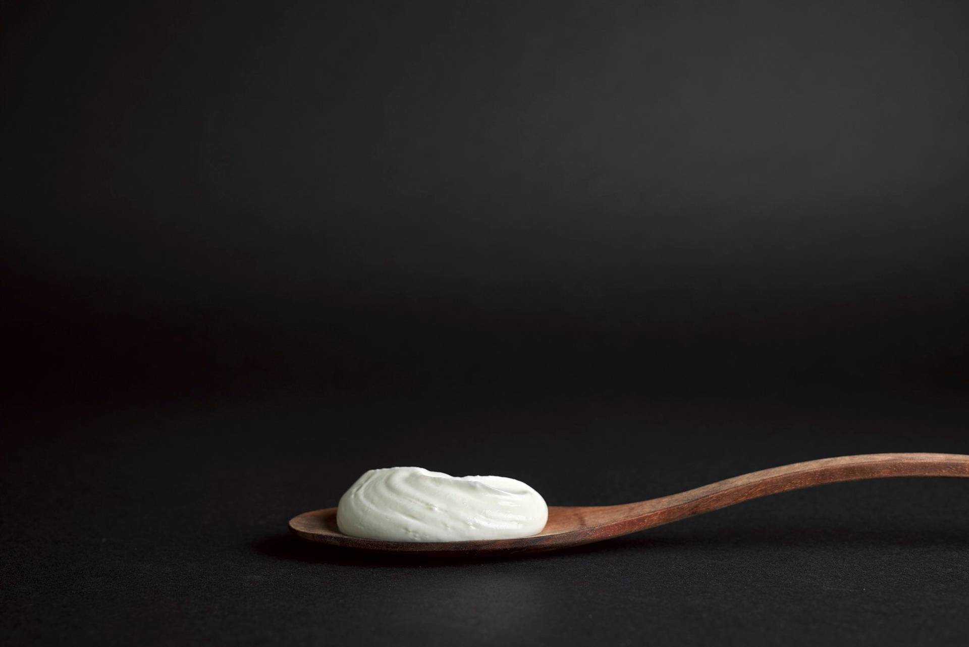 ein holzlöffel skyrbier geschmorter lauch mit pumpernickel und skyr auf einem holzbrett mit schwarzem hintergrund