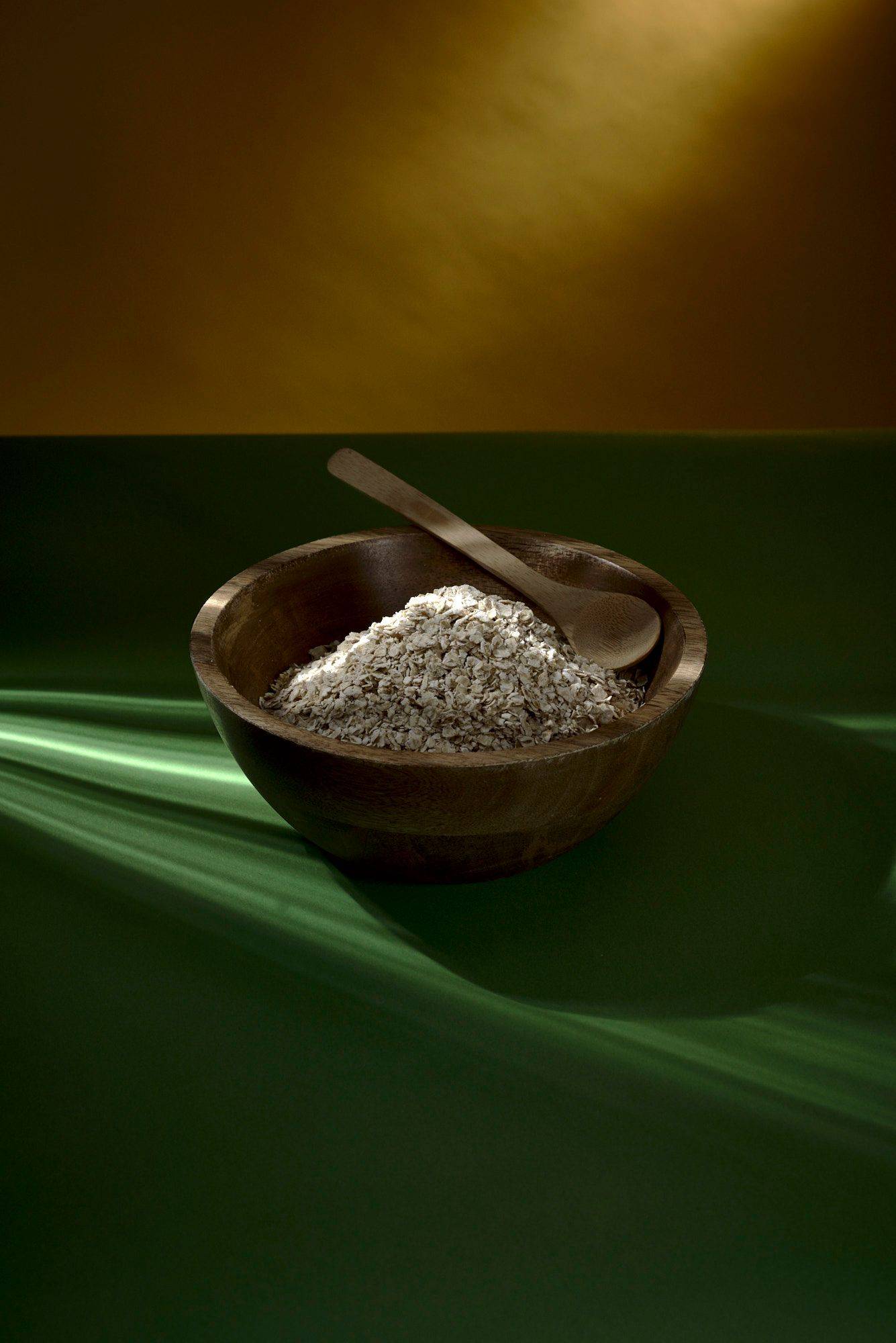 a wooden bowl with oats with green yellow background