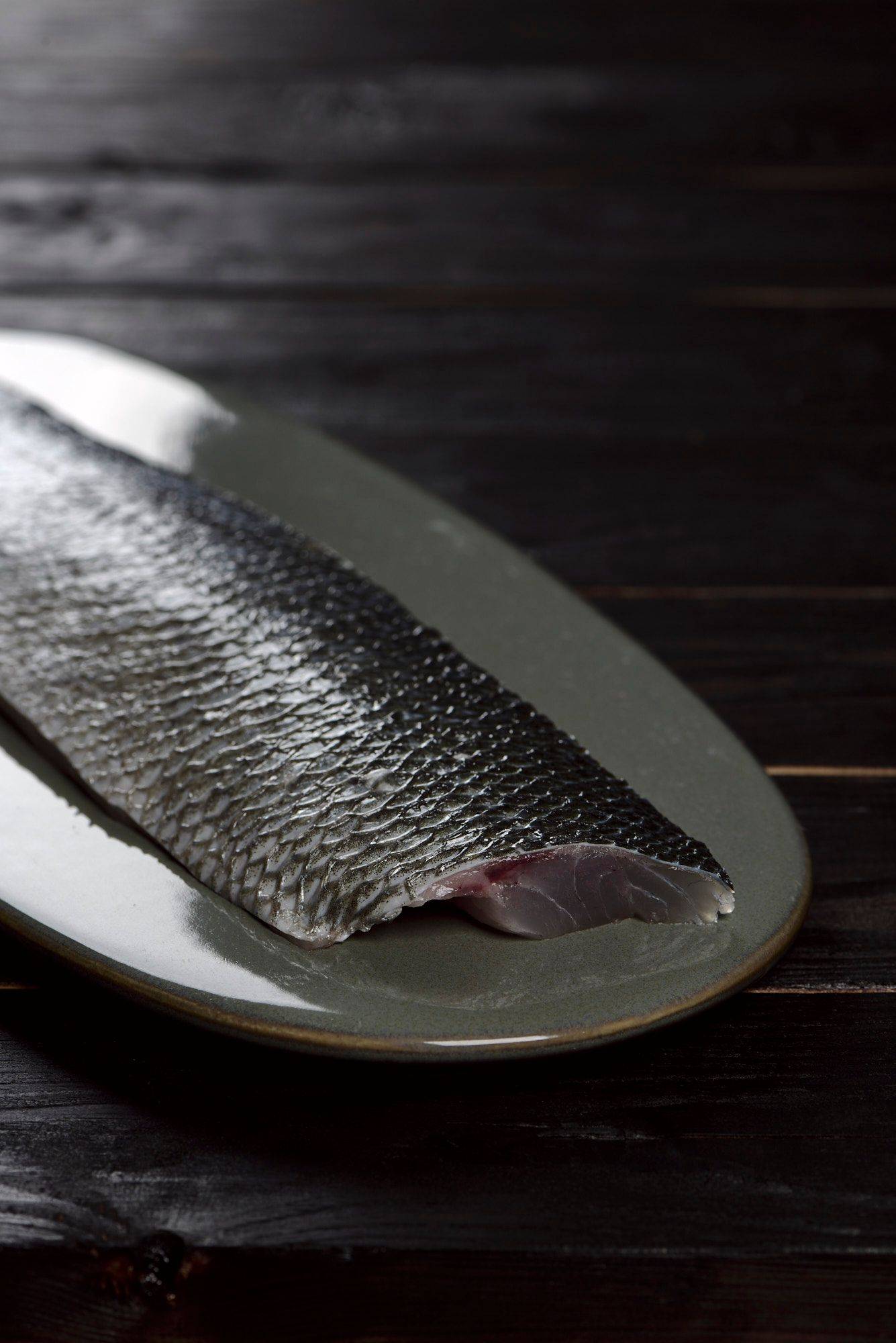 sea bass fillet on a gray plate with black wooden background