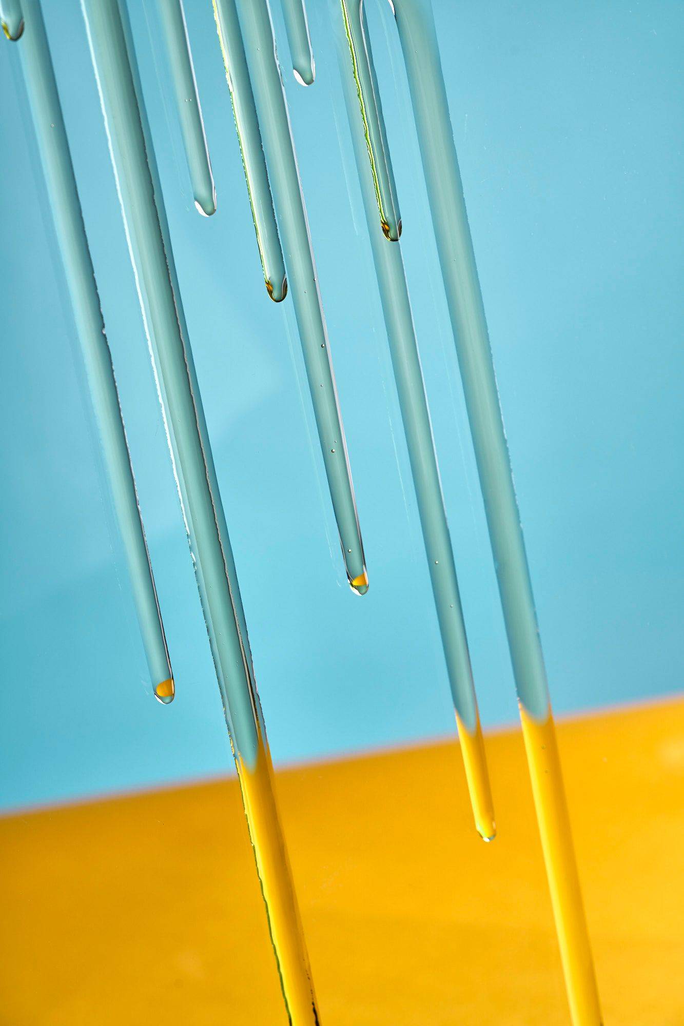 olive-oil olive oil running down a glass with yellow and blue background