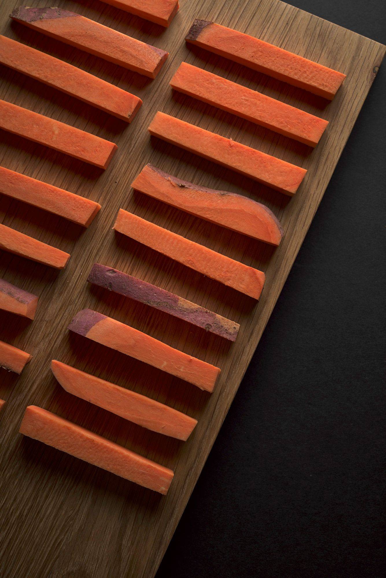 sweet potato sticks on a wooden board on black background