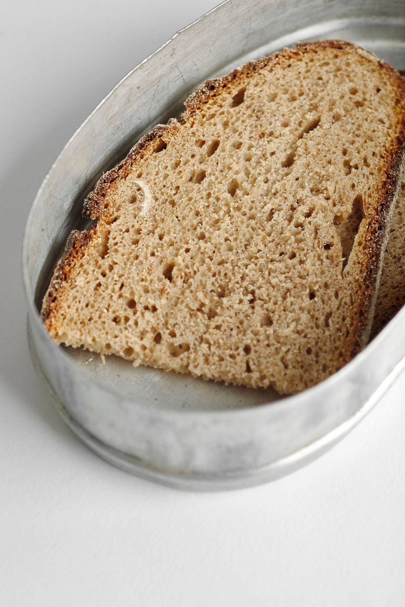 sauerteigbrot in einer alten brotdose mit weißem hintergrund