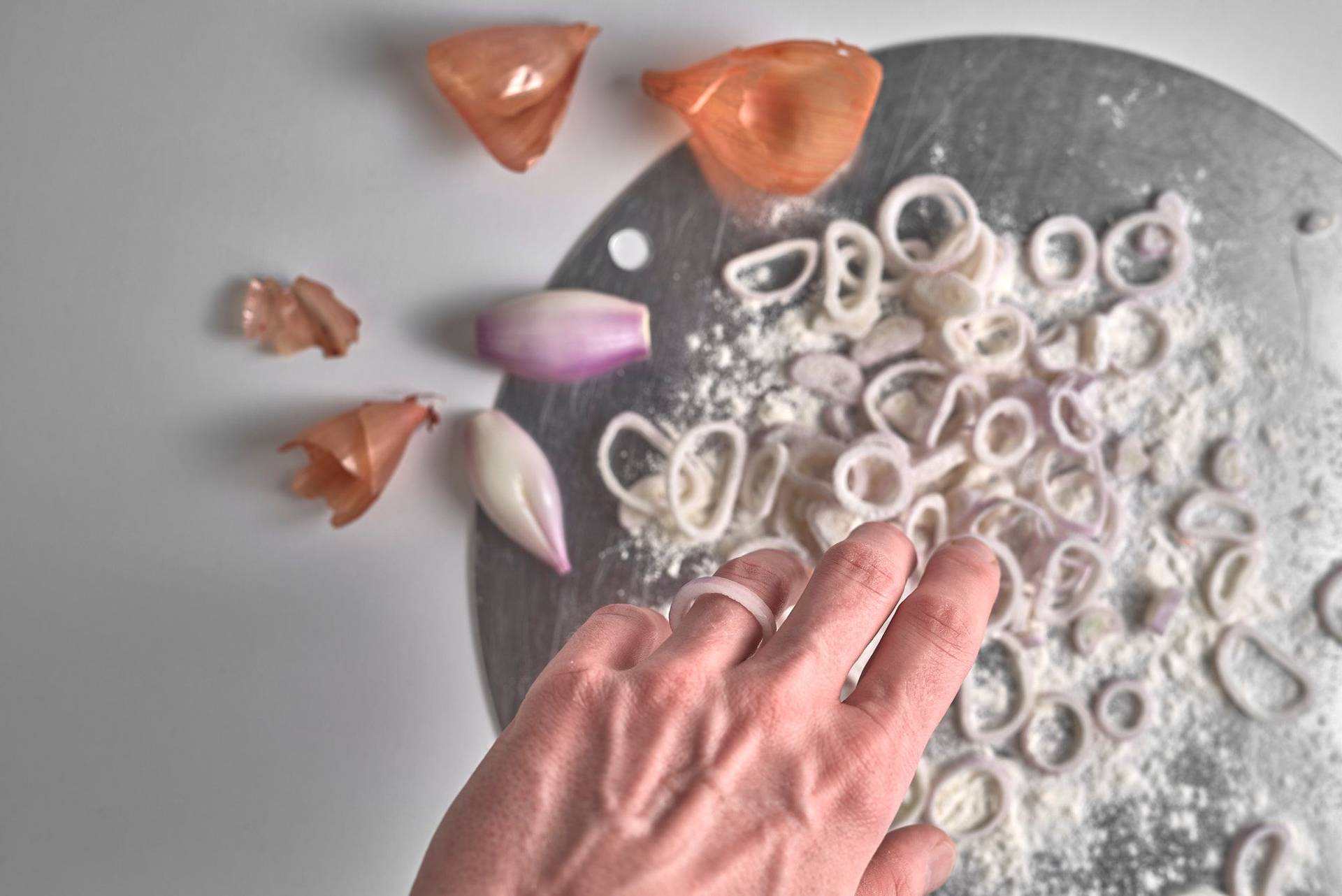 onion rings get tossed in flour on white background