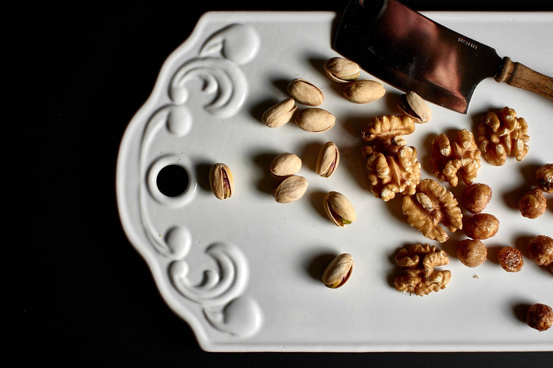 hazelnuts walnuts and pistachios on a white board with black background