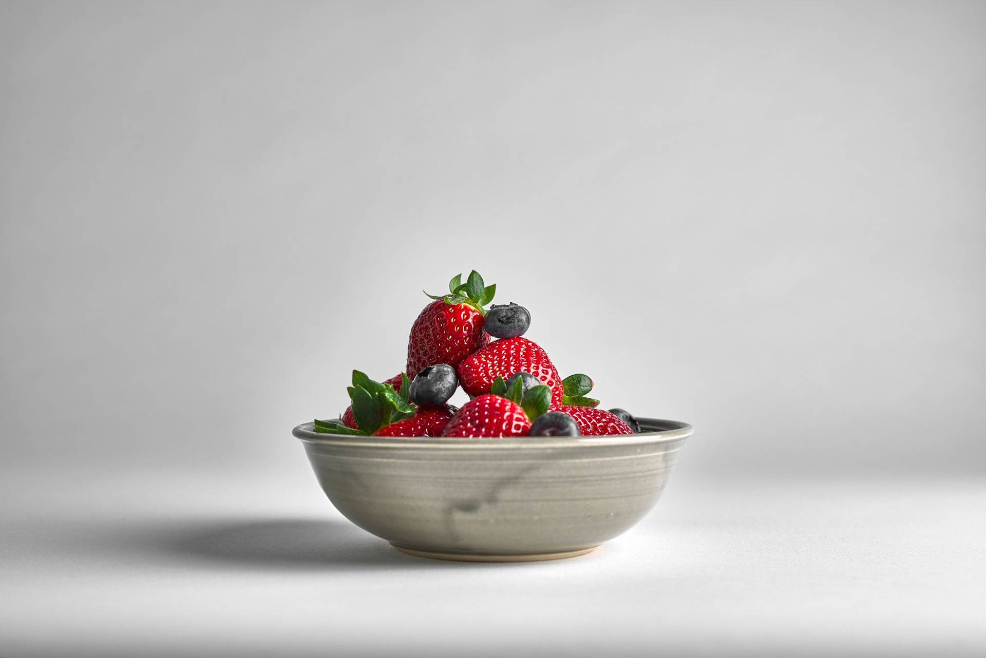 a gray bowl of mixed berries on white background