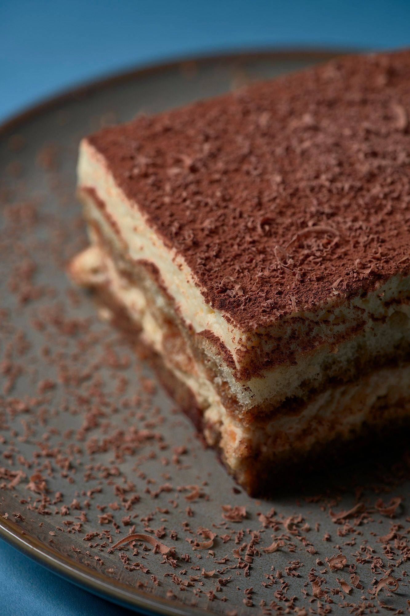 original italienisches tiramisu dessert auf grauem teller mit blauem hintergrund