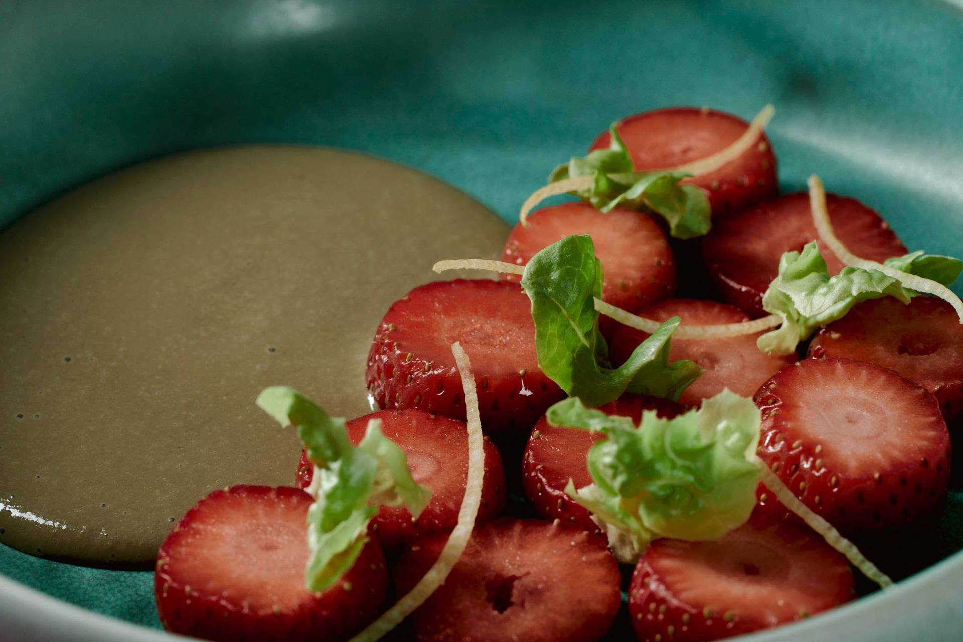 veganes erdbeerdessert mit kopfsalat und sonnenblumenkernen auf einem  türkisen teller mit pinkem hintergrund