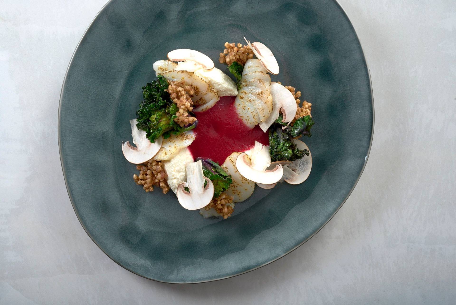 cod with beets ricotta whey and buckwheat pops on a gray plate with white sapienstone top