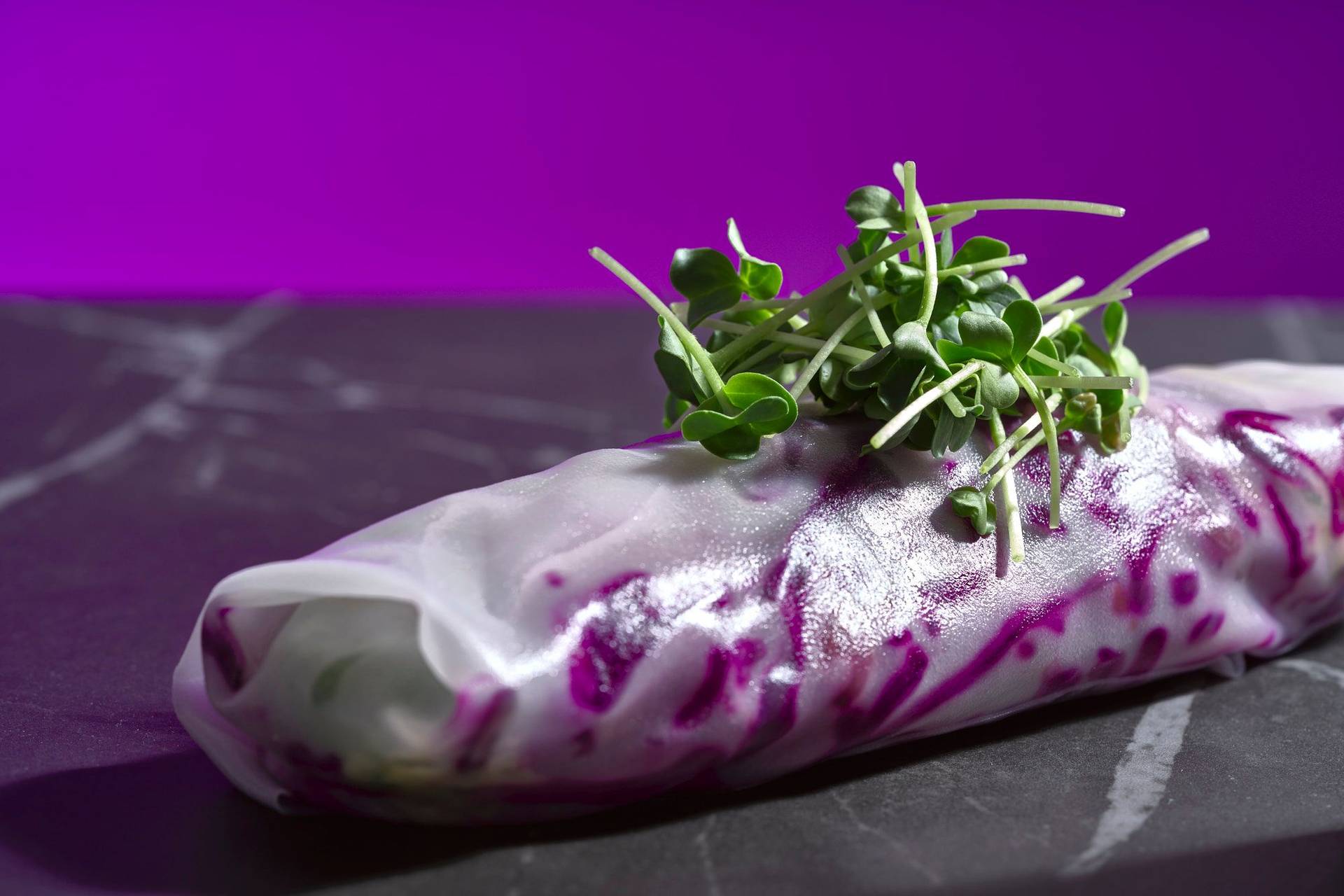 christmas summer rolls with red cabbage tangerine salad and chicken liver on a gray marbled sapienstone top with purple background