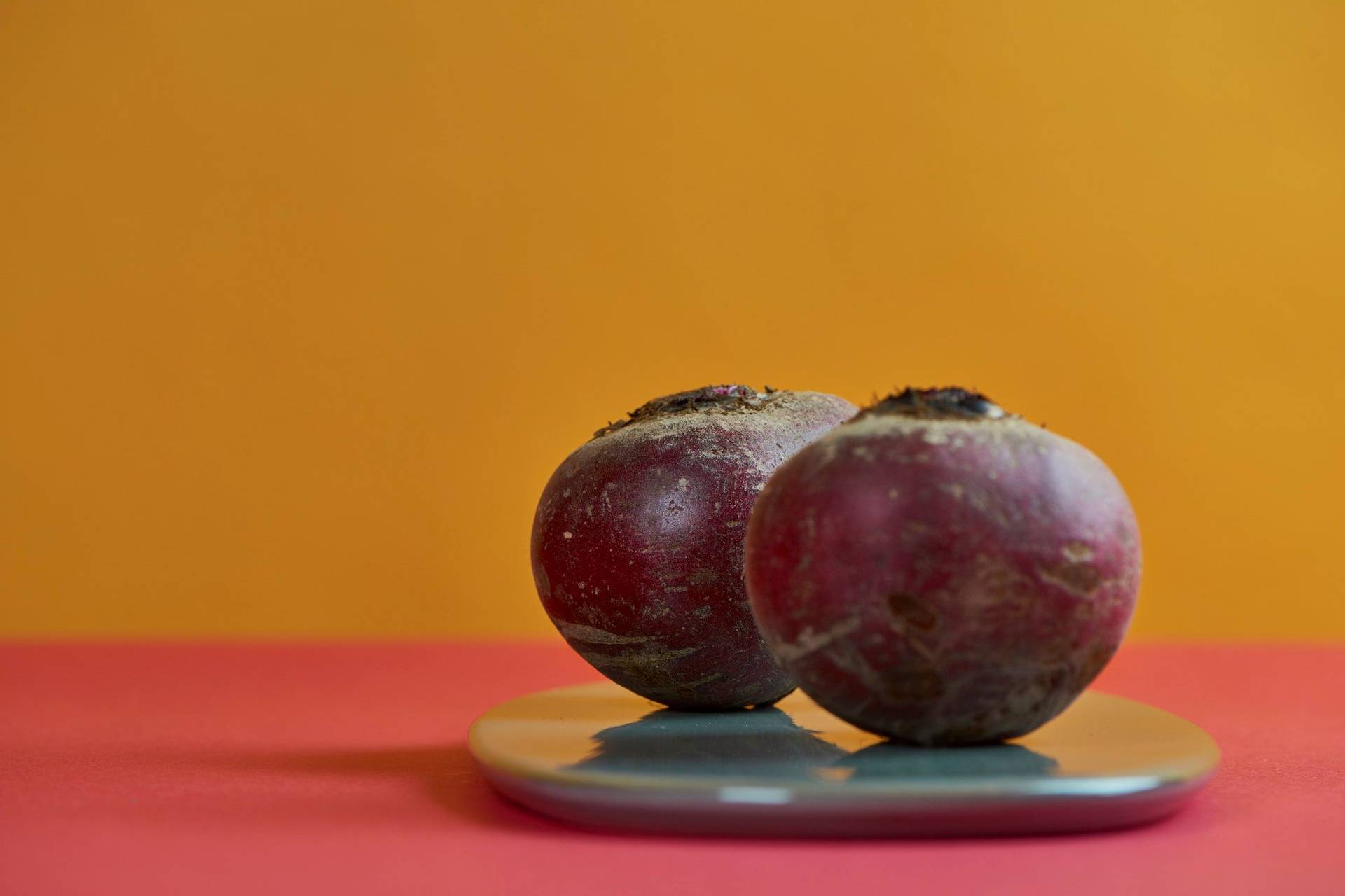beetroot two bulbs of beetroot on a gray plate with red and yellow background