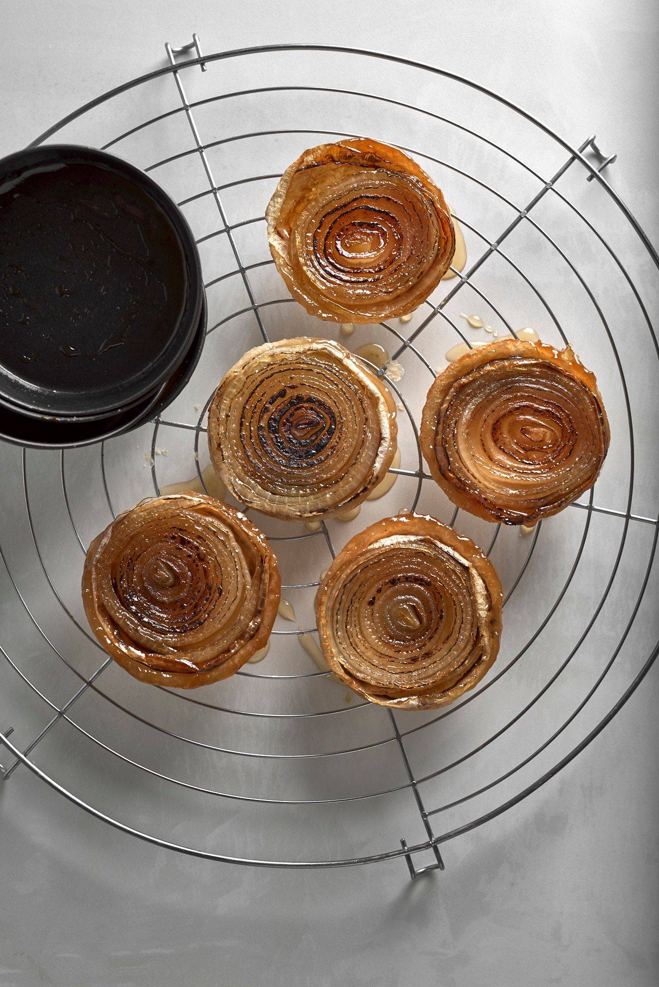 gebackene-zwiebel-tarte-tatin fünf gebackene zwiebel tarte tatins auf einem gitter mit weißem steintisch