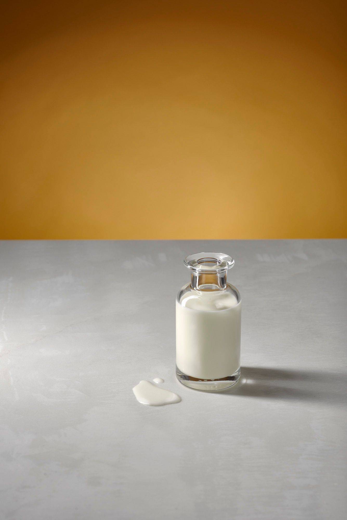 cream in a glass bottle with white sapienstone top and yellow background
