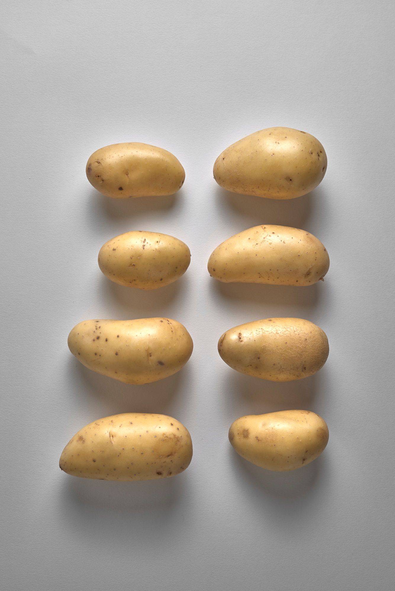 eight potatoes in a row on white background