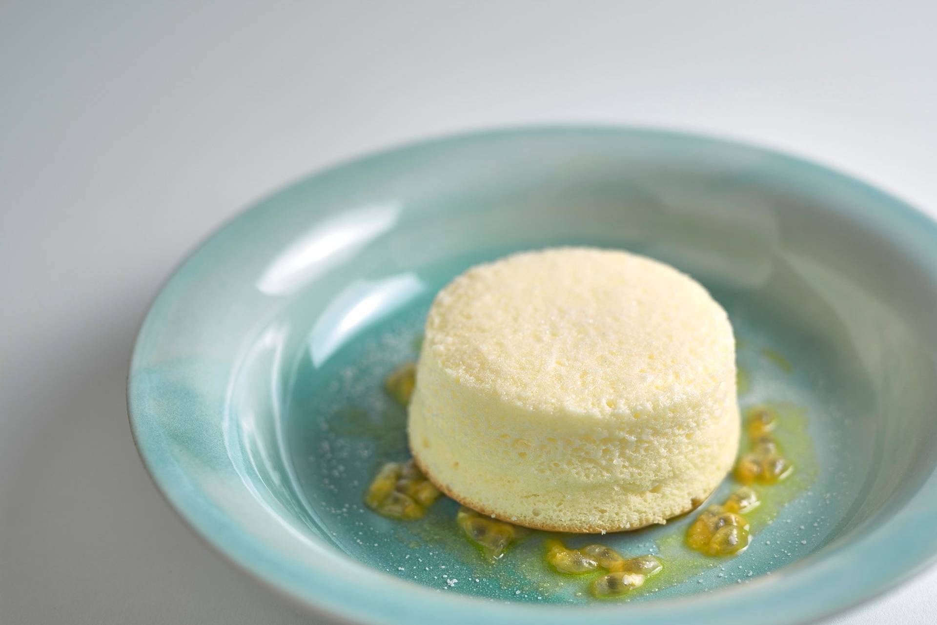 cheesecake souffle with passion fruit and linseed oil in a turquoise plate with white background