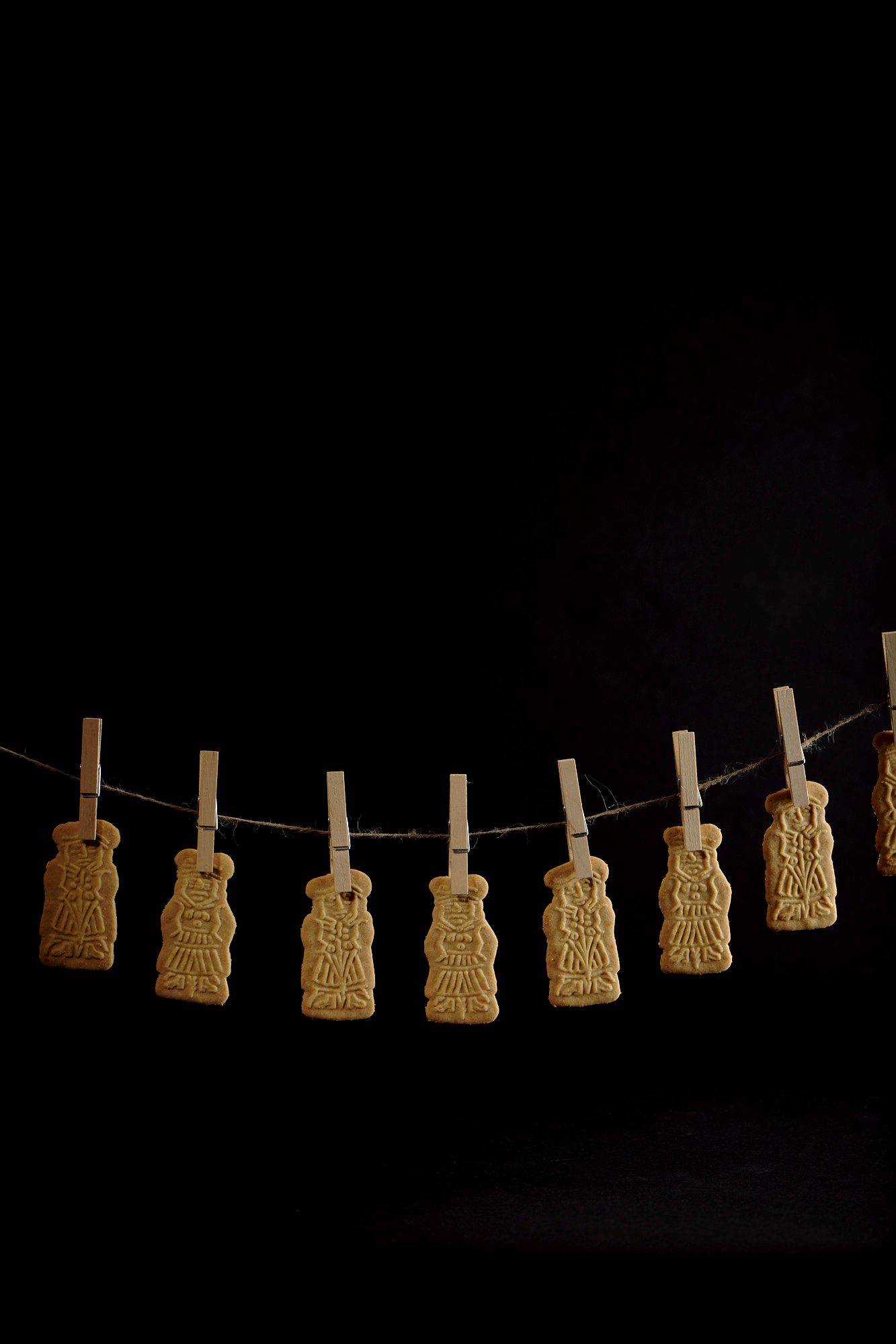 speculoos cookies hanging on a string with black background
